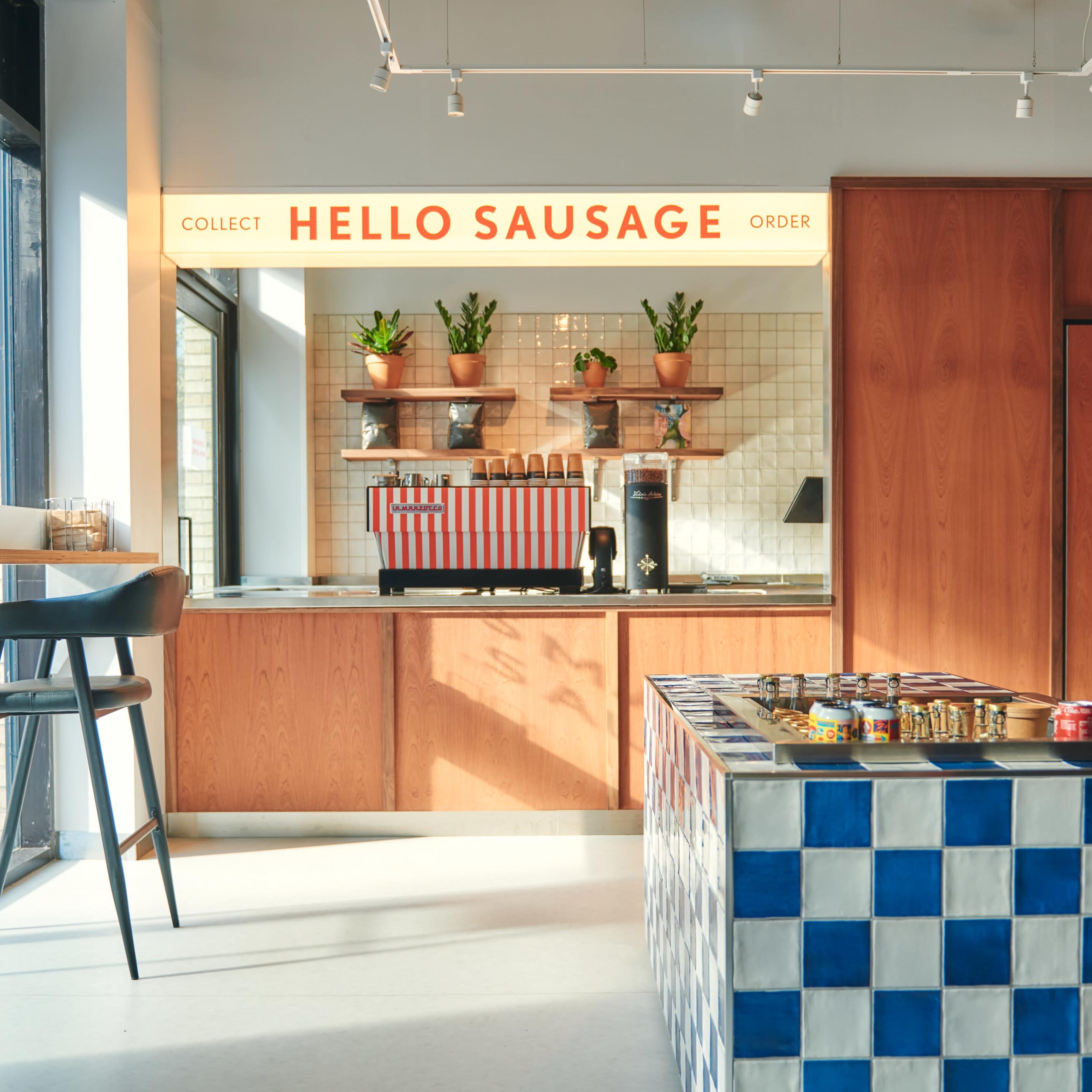 A modern food service area with a counter displaying products, potted plants on shelves, and a blue and white patterned table in the center.