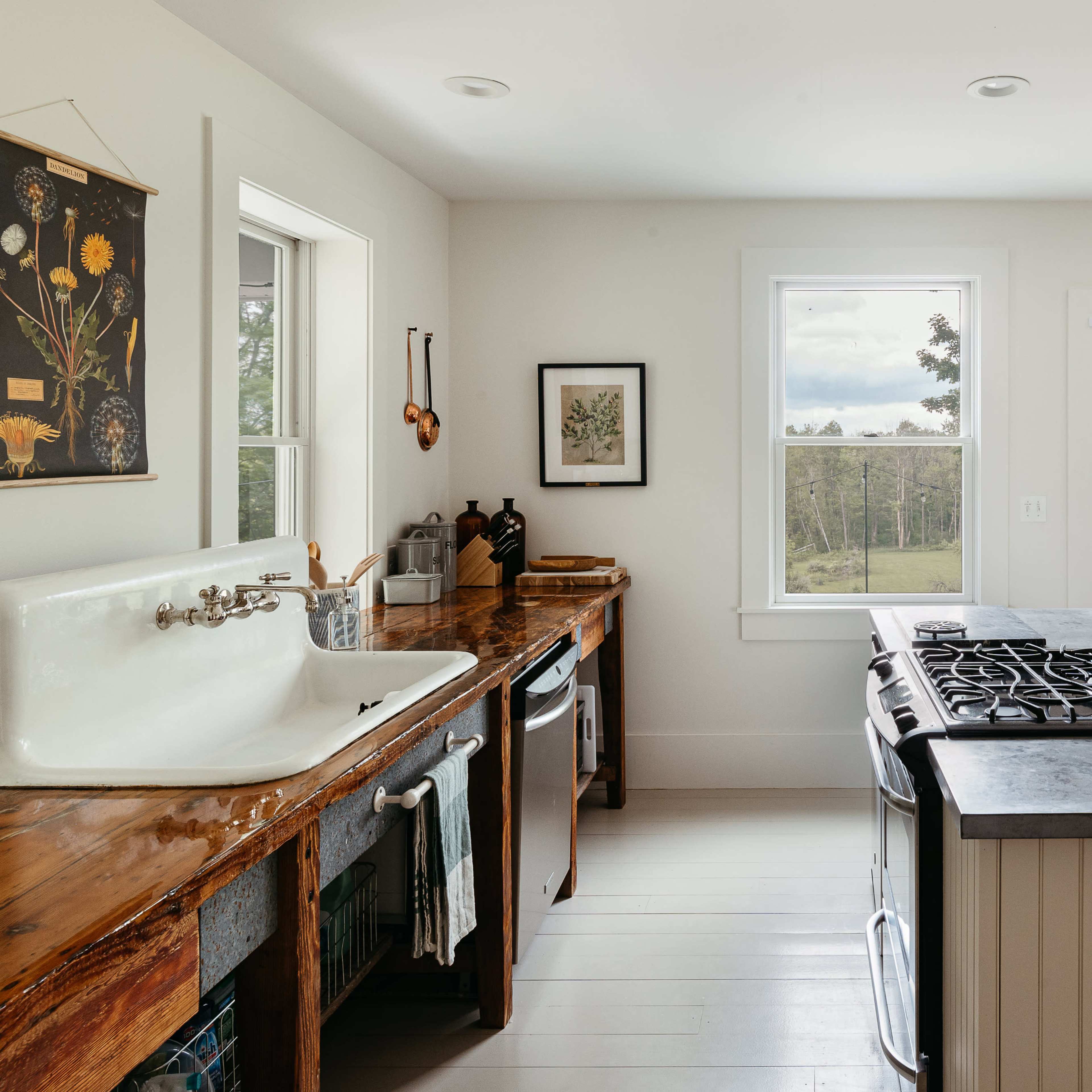 A kitchen with a farmhouse sink, a stove island, large windows letting in natural light, and a door leading outside.