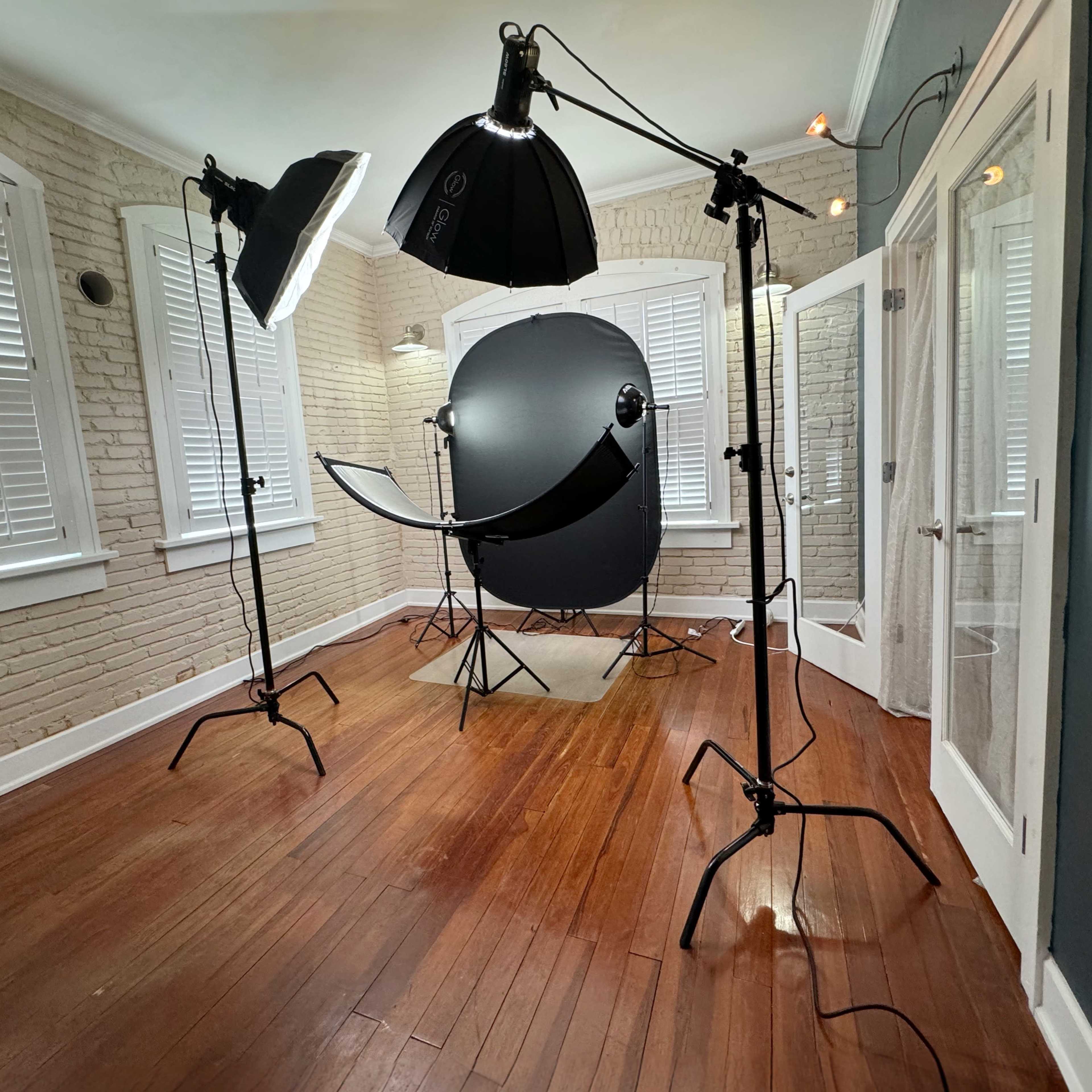 A photography studio with lighting equipment, a backdrop, and wooden flooring.