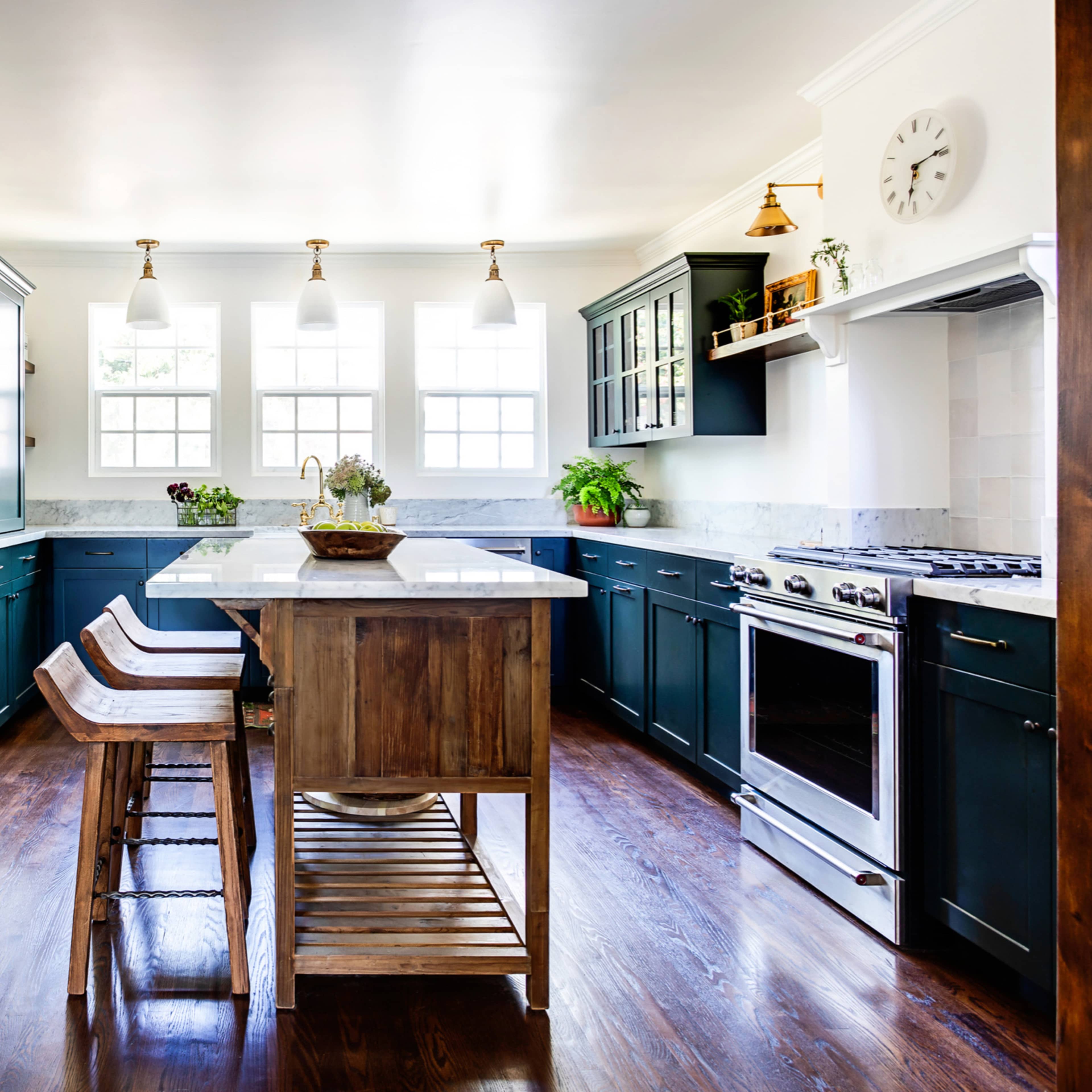 A modern kitchen features dark cabinetry, a central island with a wooden base, and stainless steel appliances.