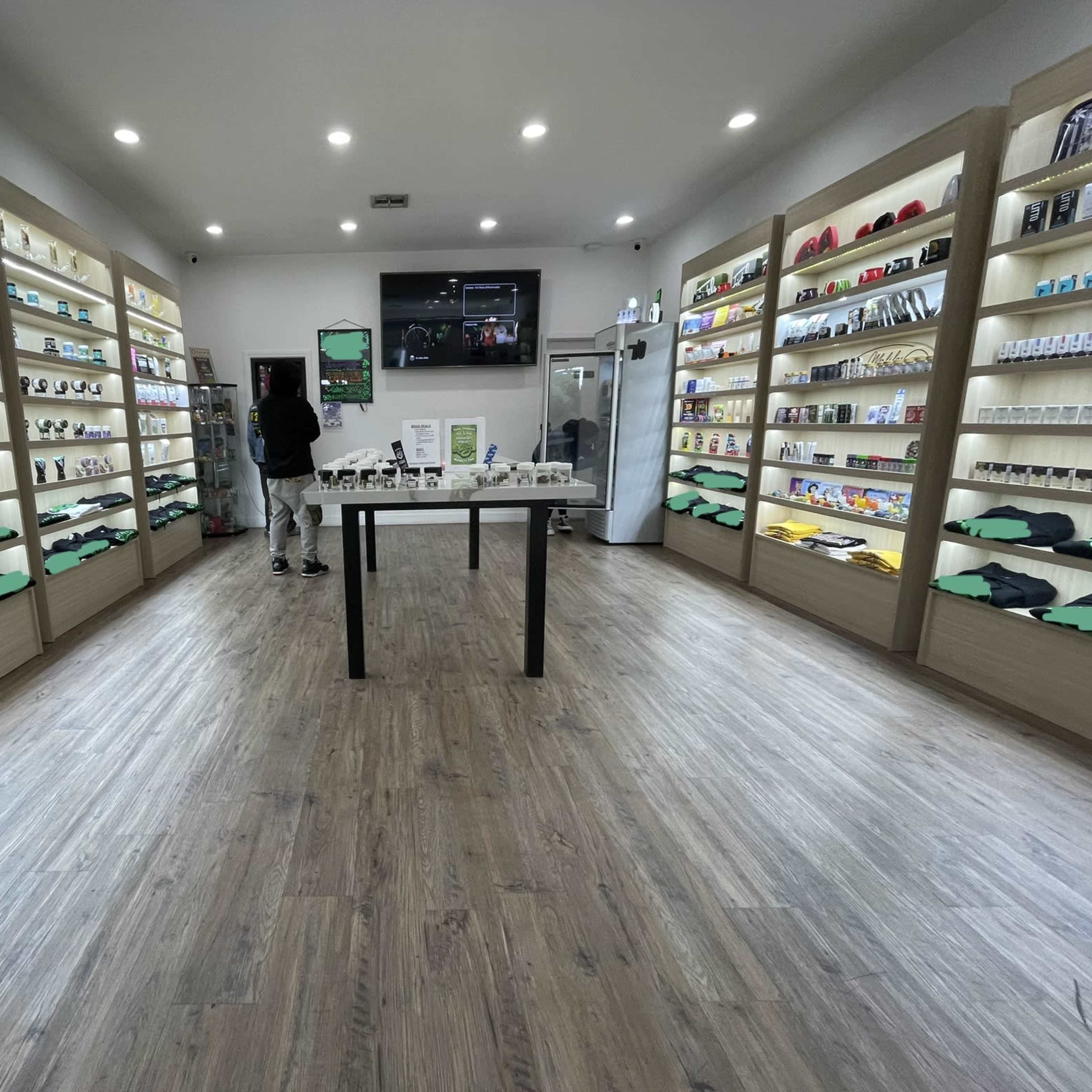 A well-organized retail space with products displayed on shelves lining the walls and a central table in a brightly lit environment.