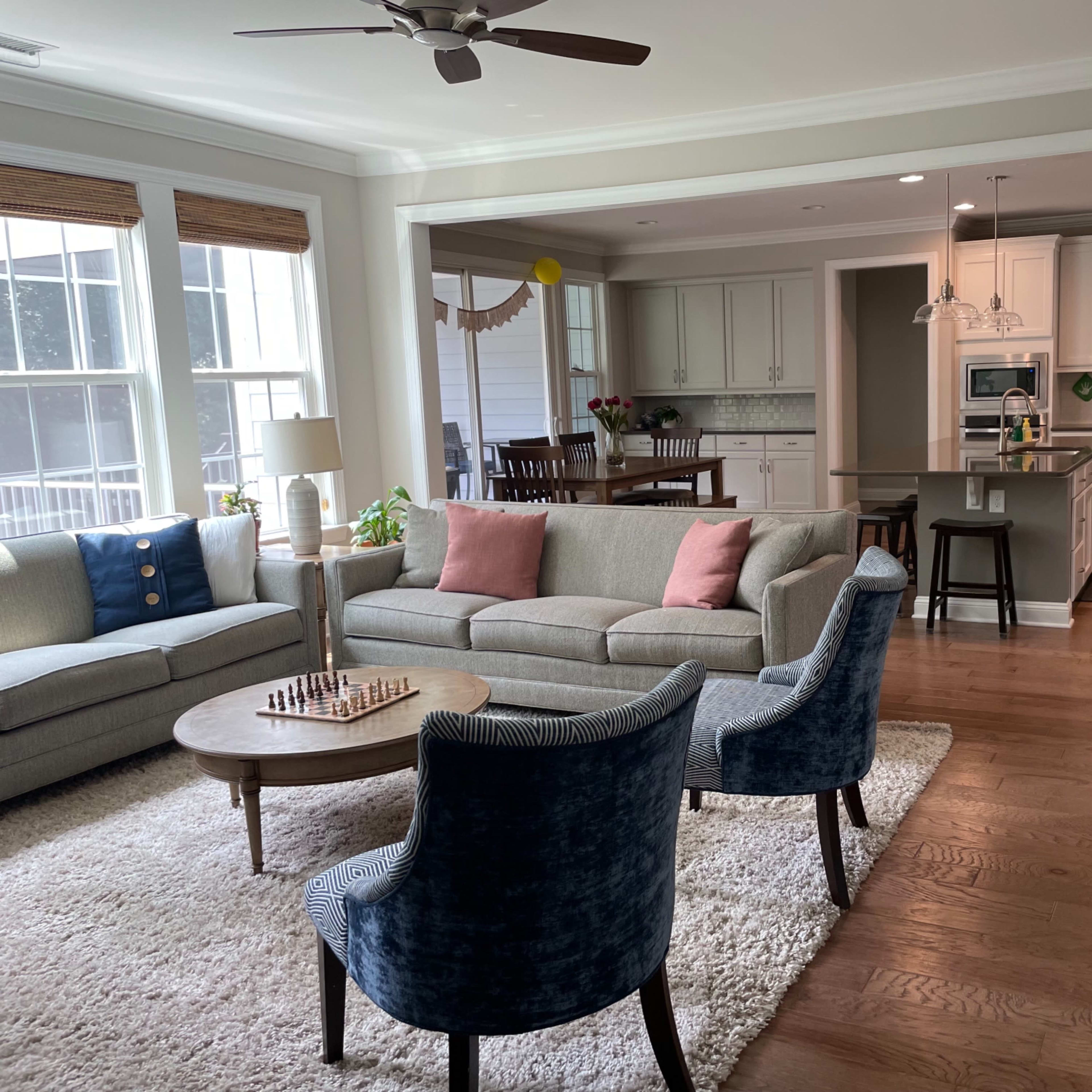 A modern, open-concept living room and kitchen area with a gray sectional sofa, a round table, and a kitchen island.