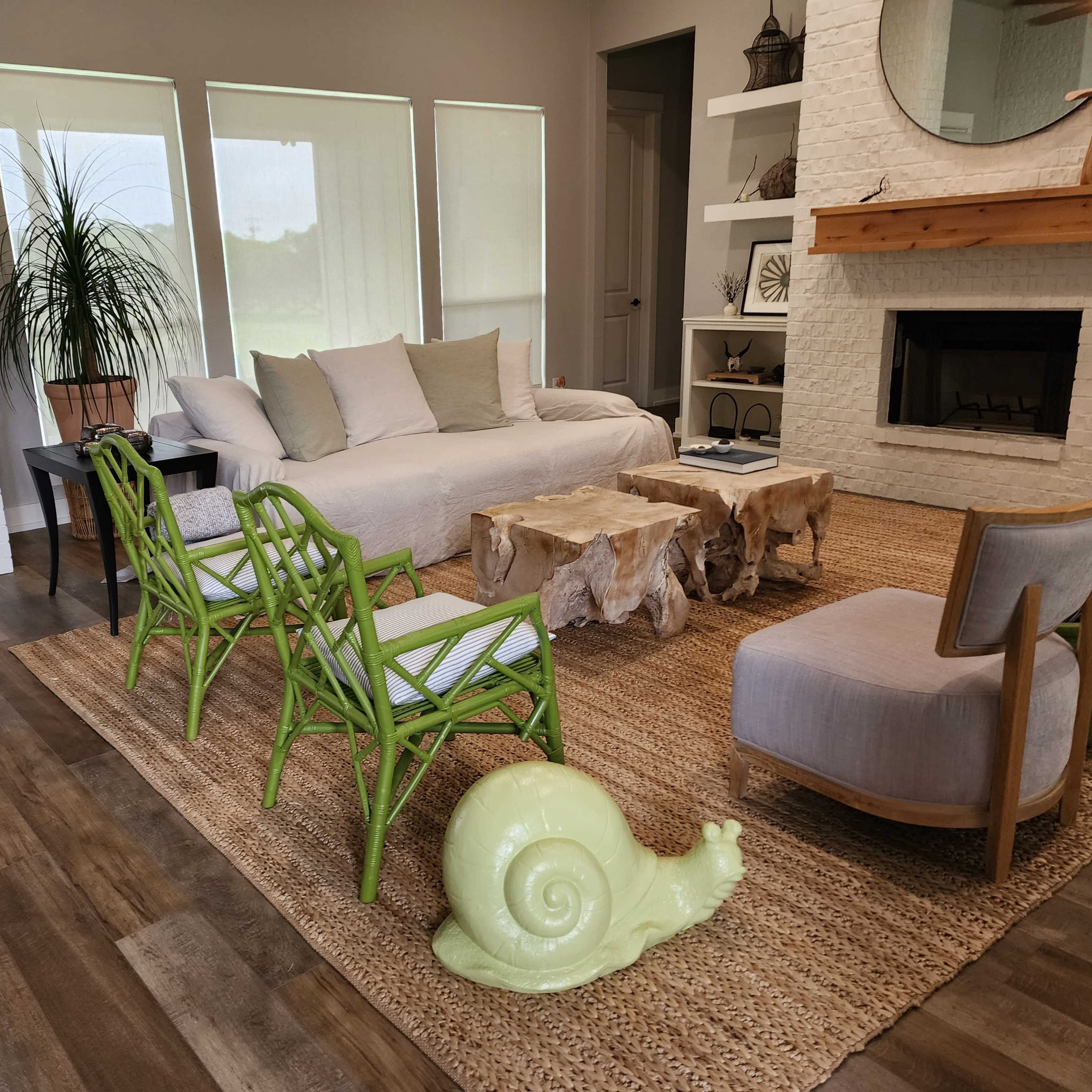 The living room features a light-colored sofa, a pair of wooden coffee tables, and colorful chairs, all arranged around a central area rug.