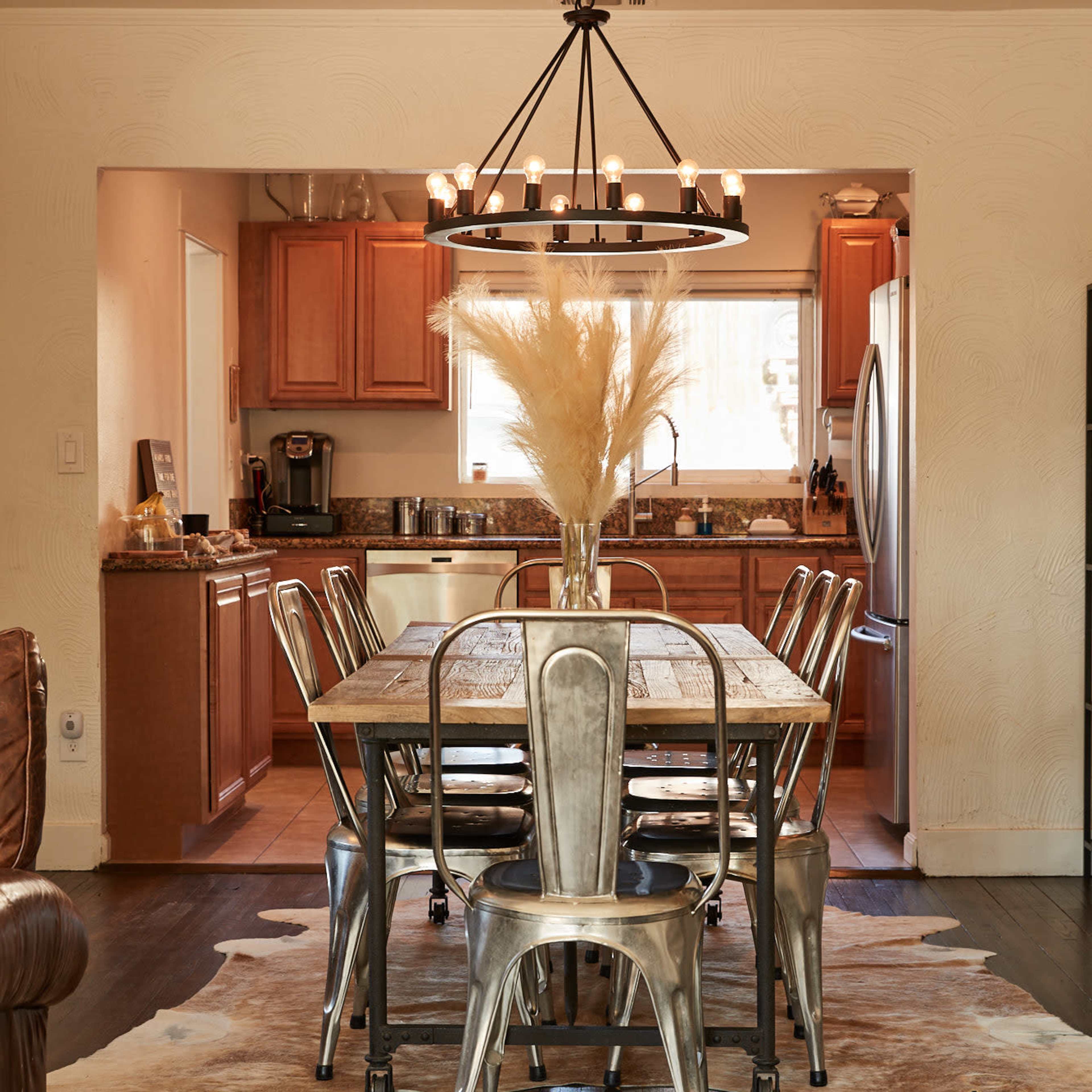 A dining area features a wooden table surrounded by metal chairs, with a kitchen visible in the background.