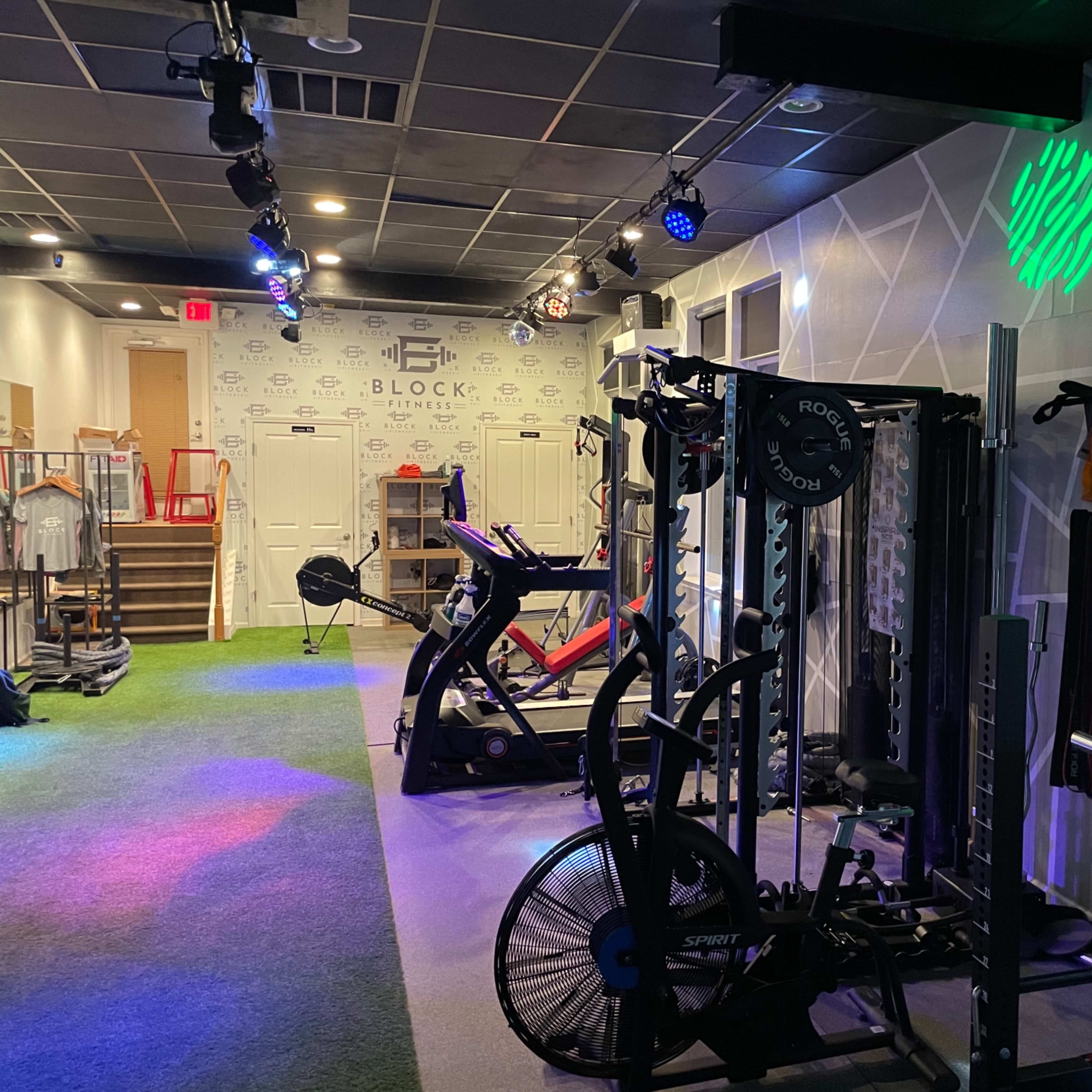 A fitness studio equipped with exercise machines, strength training equipment, and colorful lighting.