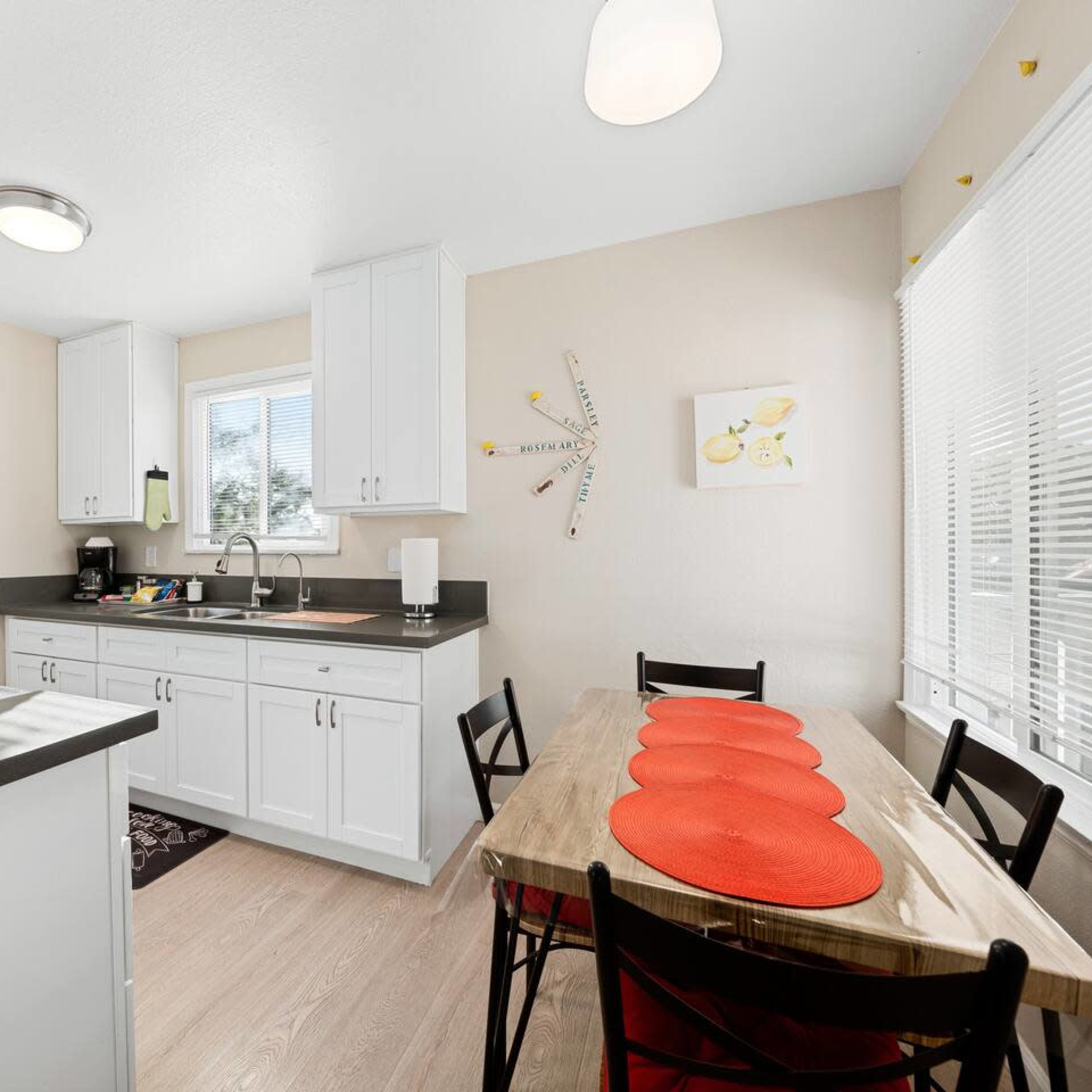 The kitchen features white cabinetry, a gray countertop, and a small dining table with red placemats.