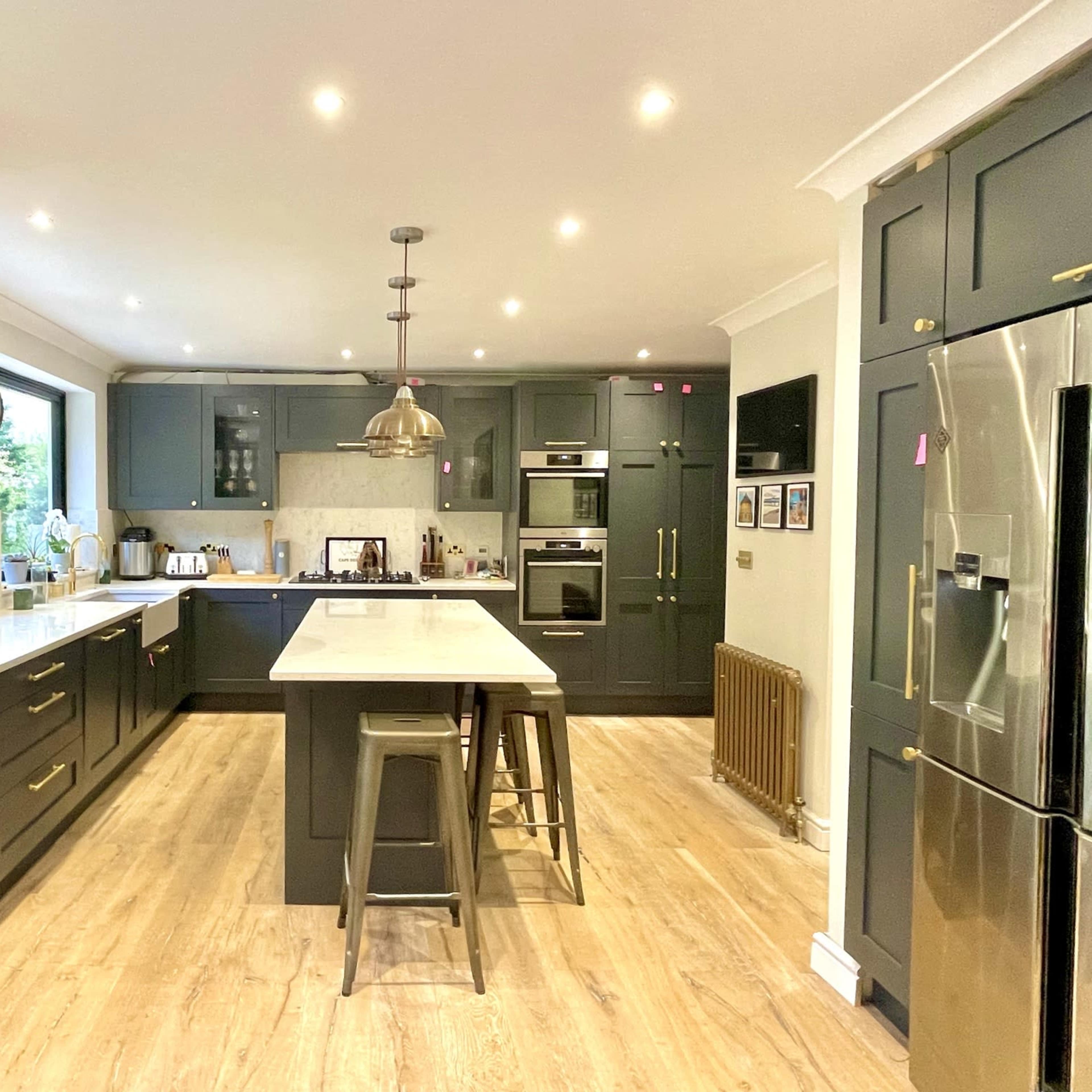 A modern kitchen featuring dark cabinetry, a central island with seating, and stainless steel appliances.
