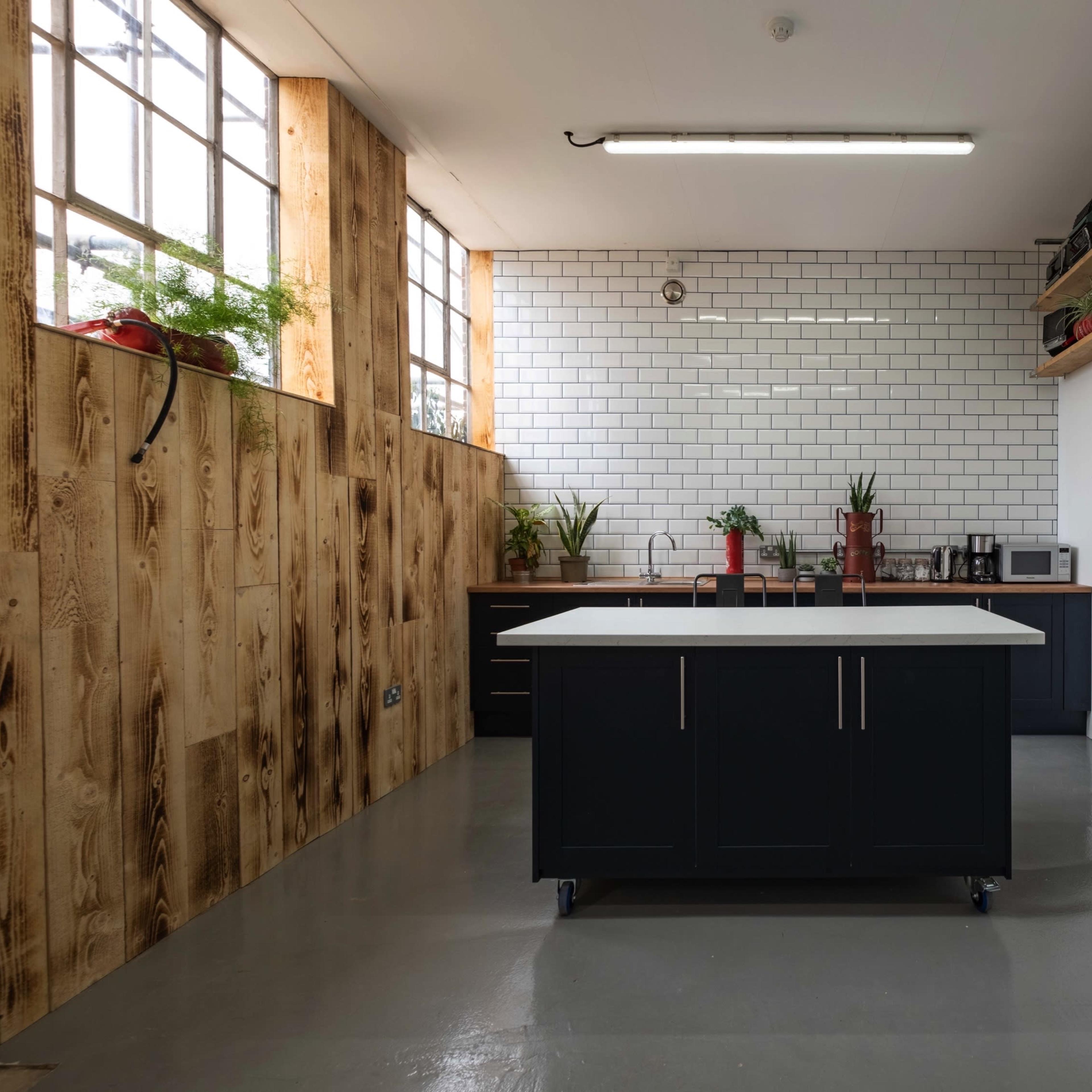 A modern kitchen features a central island, white subway tile backsplash, and wooden accents against a minimalist design.