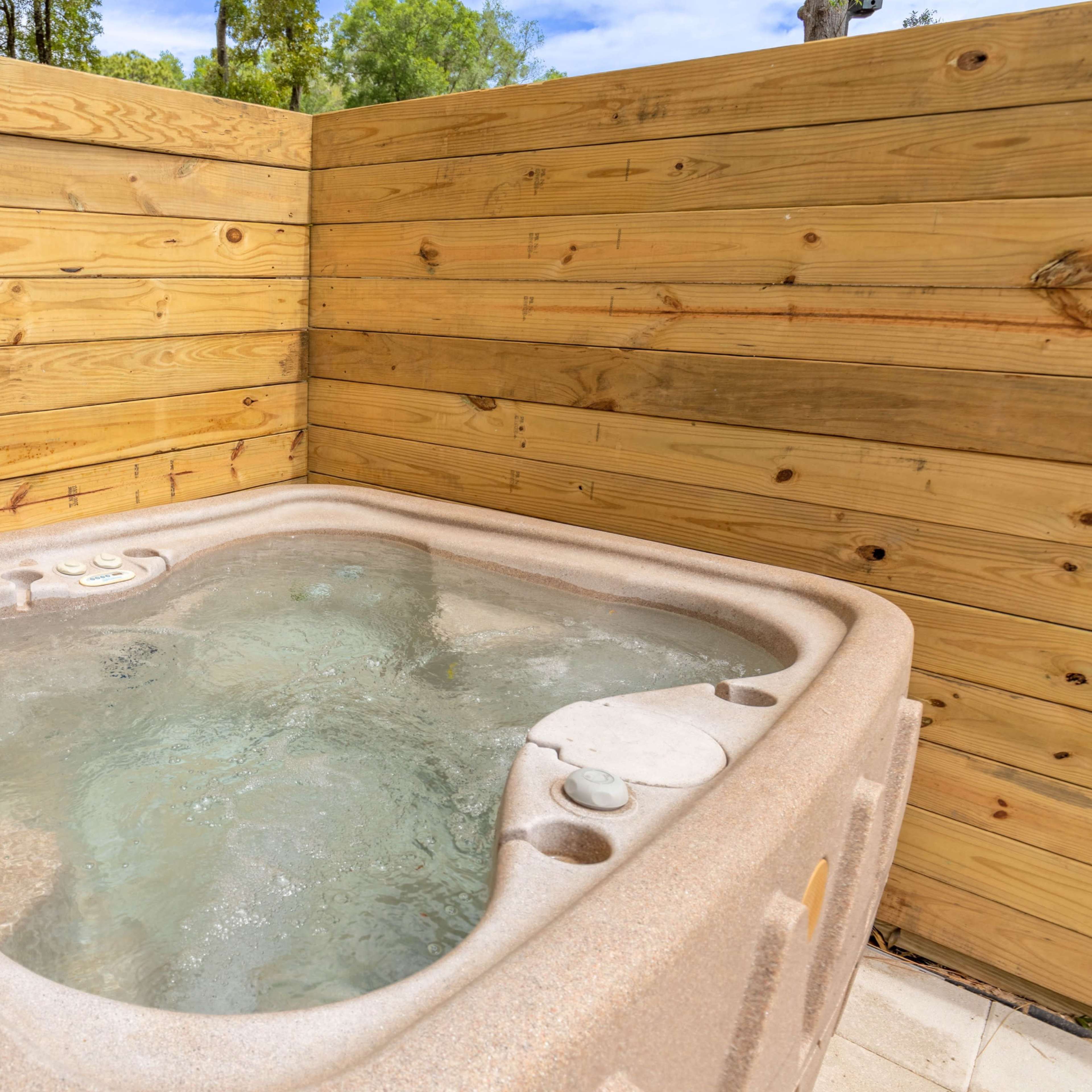 A hot tub with bubbling water is situated in a wooden enclosure.