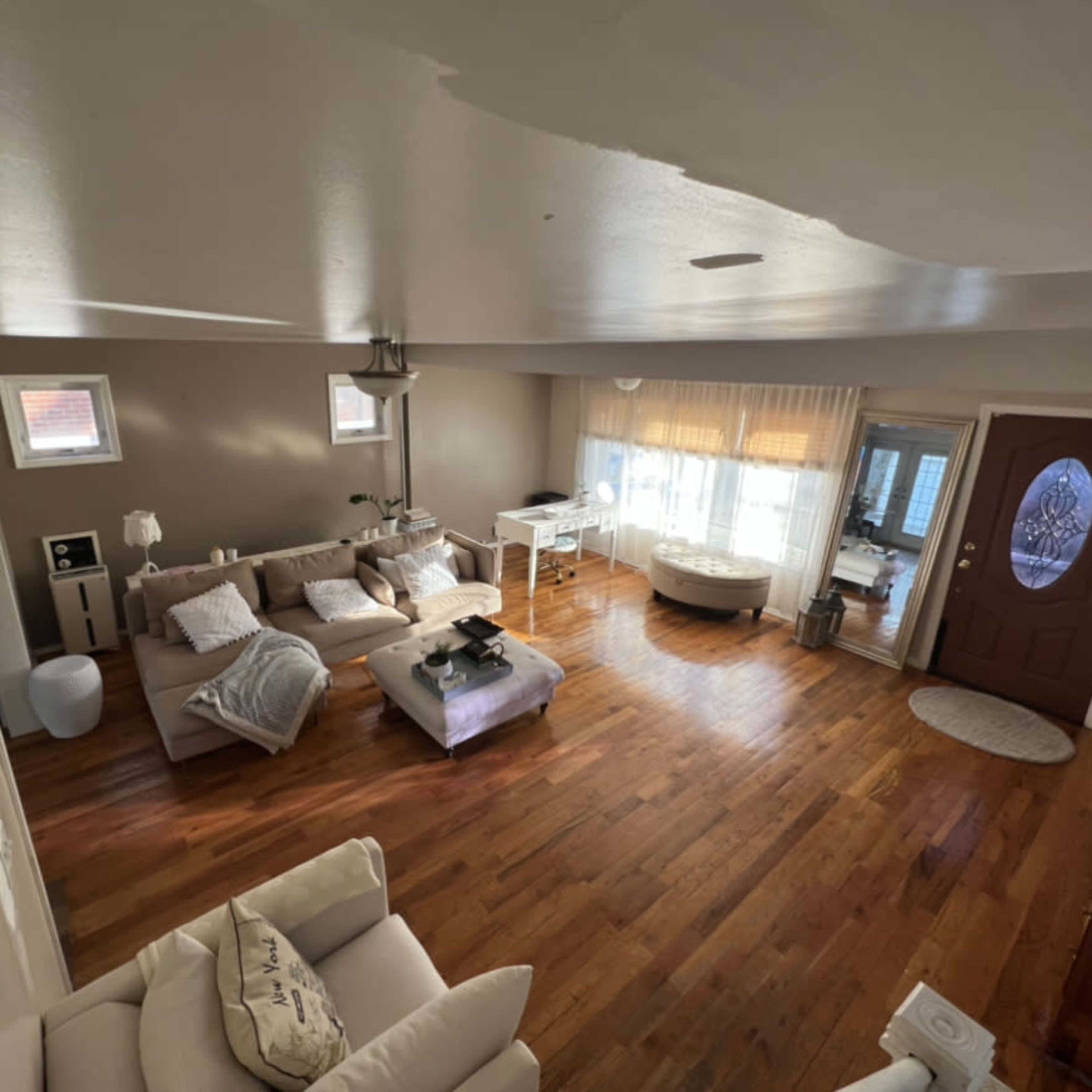 A spacious living room with hardwood flooring, a couch, coffee table, and a front door leading outside.