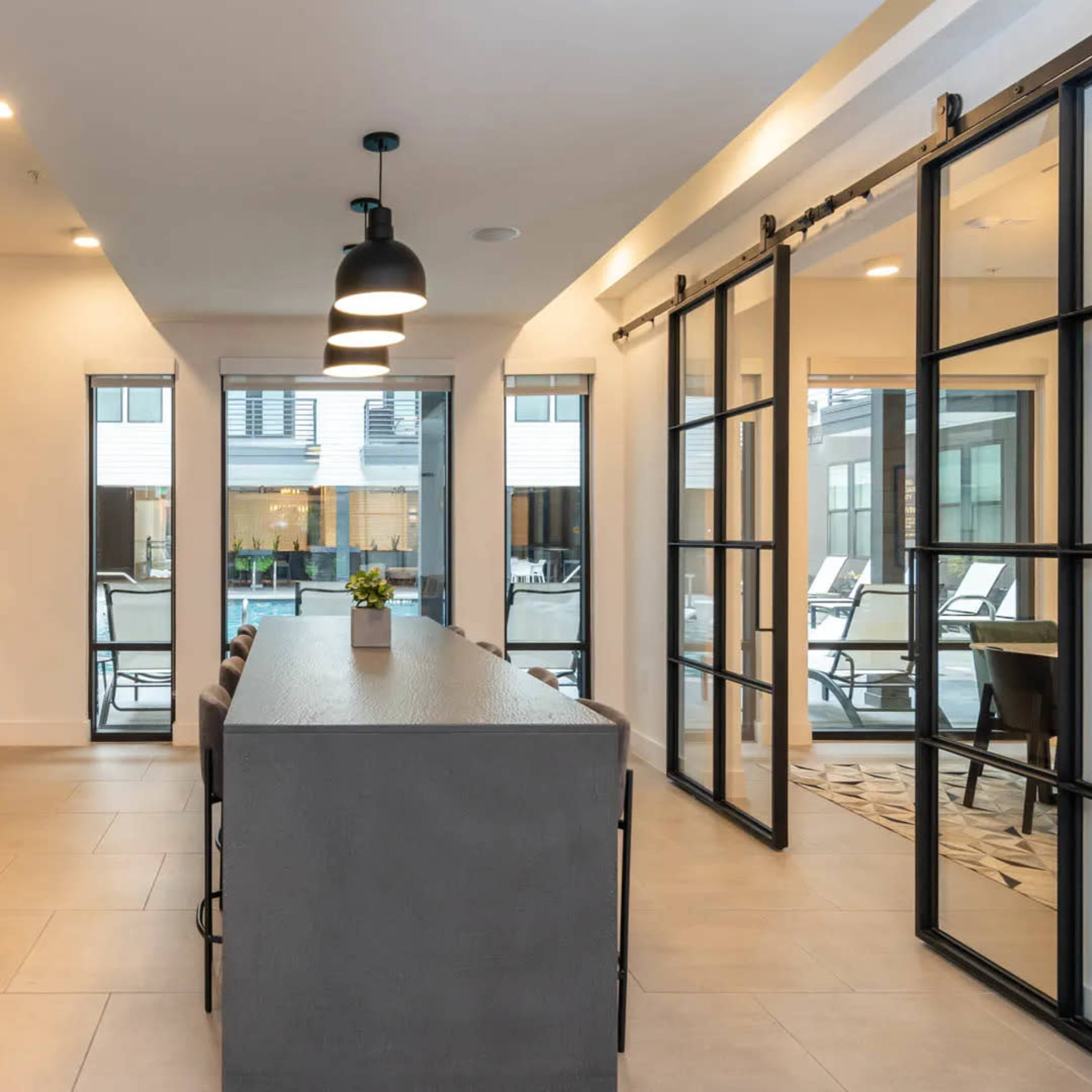 A modern kitchen with a long island, stainless steel appliances, and large windows that open to an outdoor patio area.