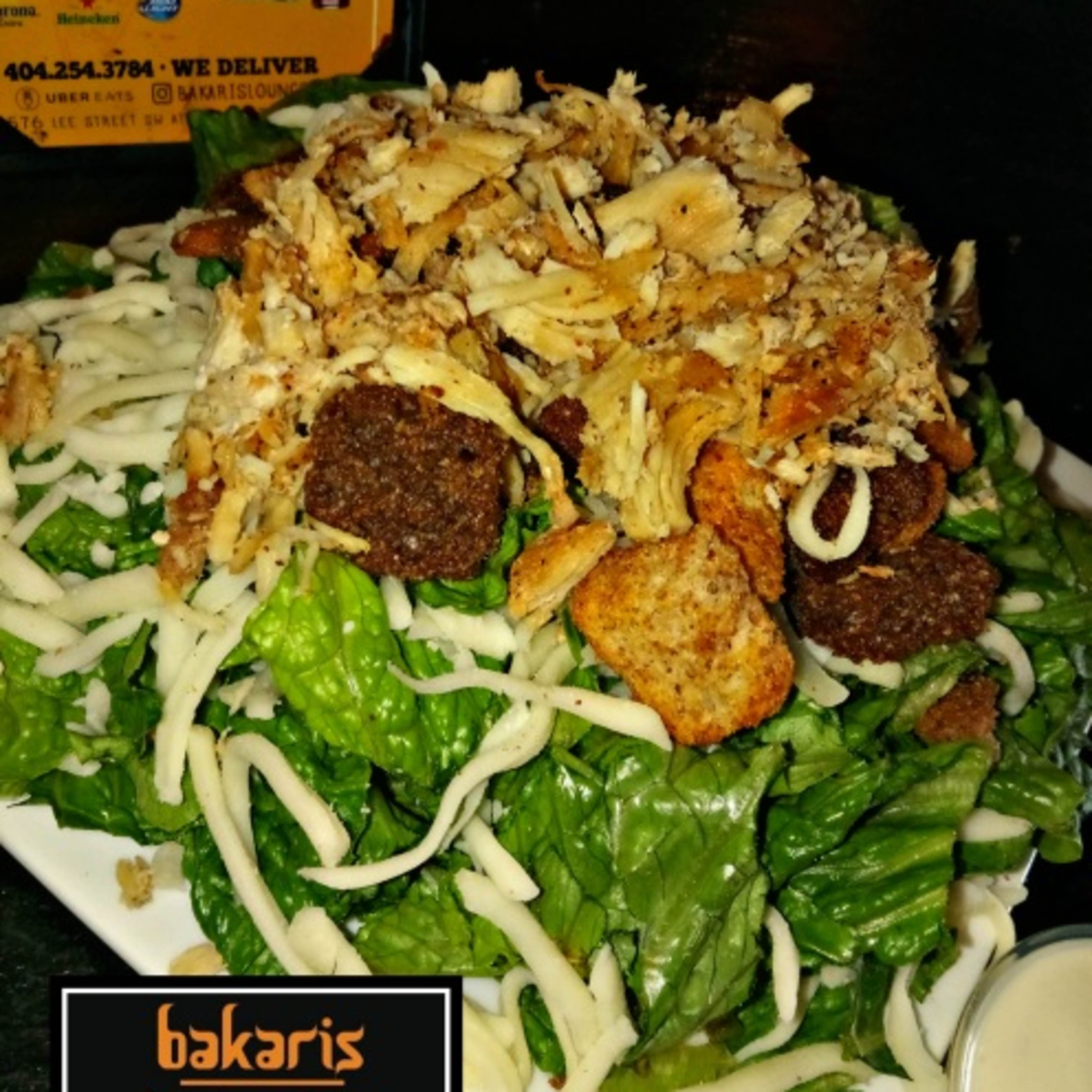 A large salad topped with crispy fried onions, croutons, and shredded cheese is served in a bowl.
