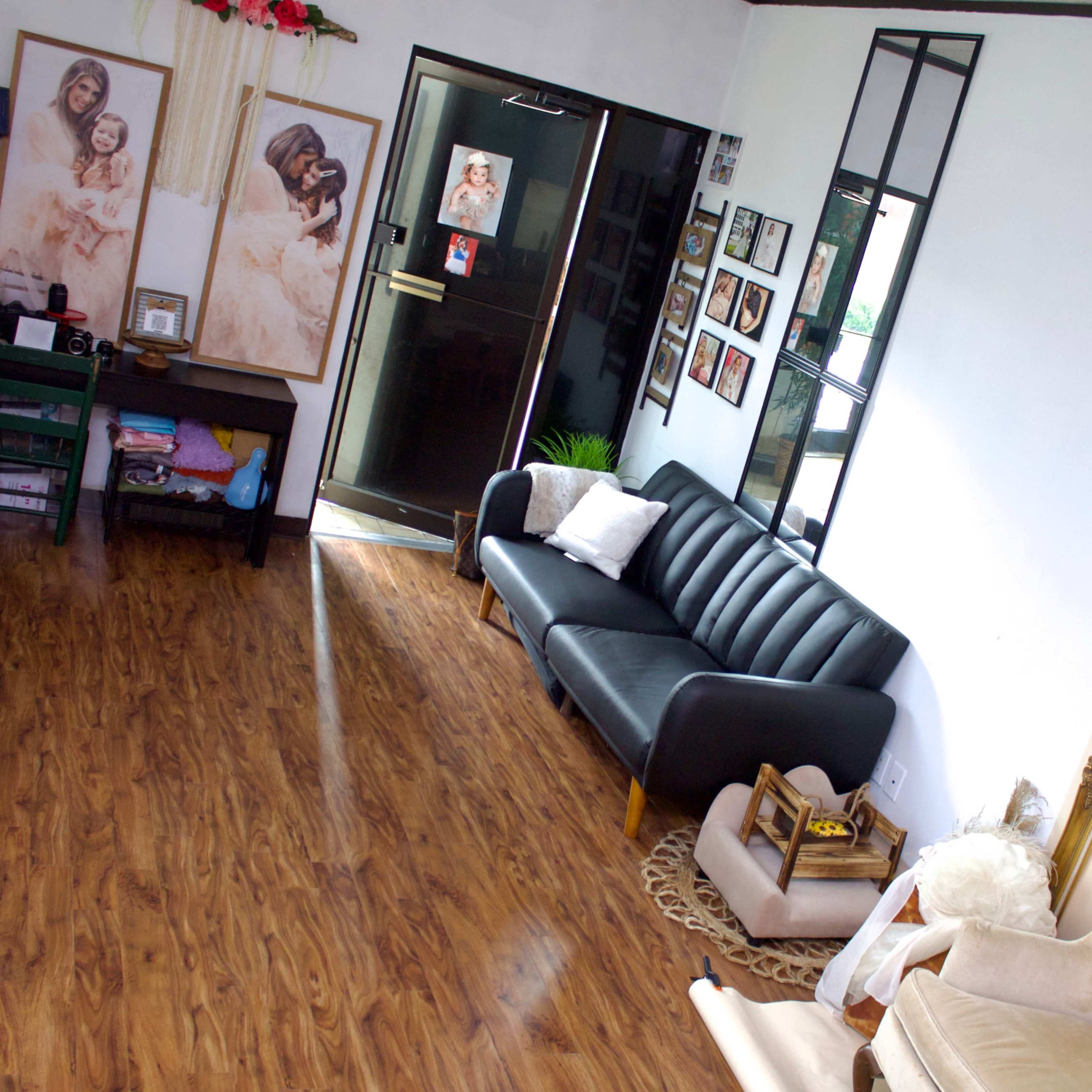 A spacious living room with two sofas, wooden flooring, and framed photographs on the walls.