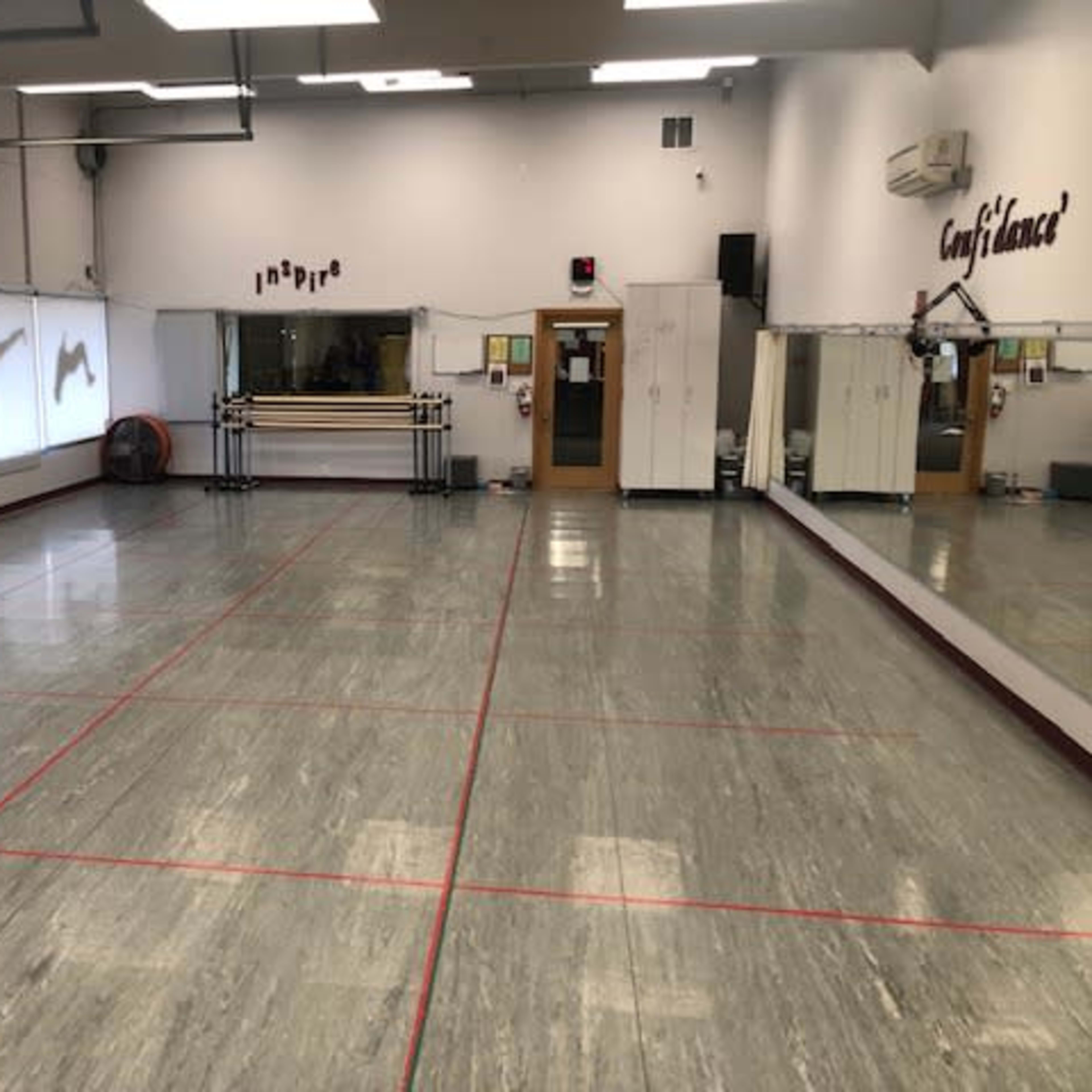 A dance studio with mirrored walls, a smooth floor, and silhouettes of dancers projected on one wall.