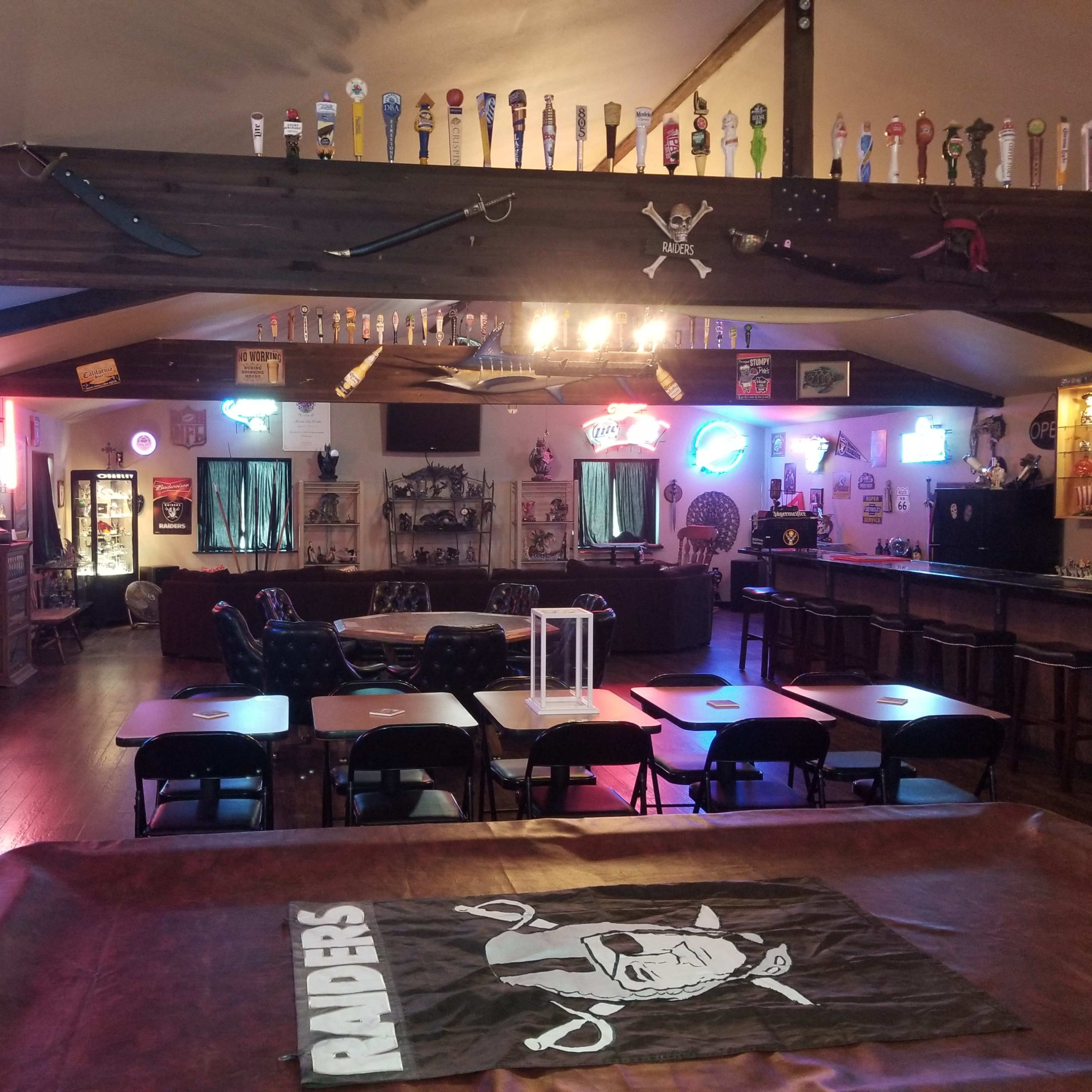A recreational room with a bar area, seating arrangements, and various decorations, including neon signs and wall-mounted memorabilia.