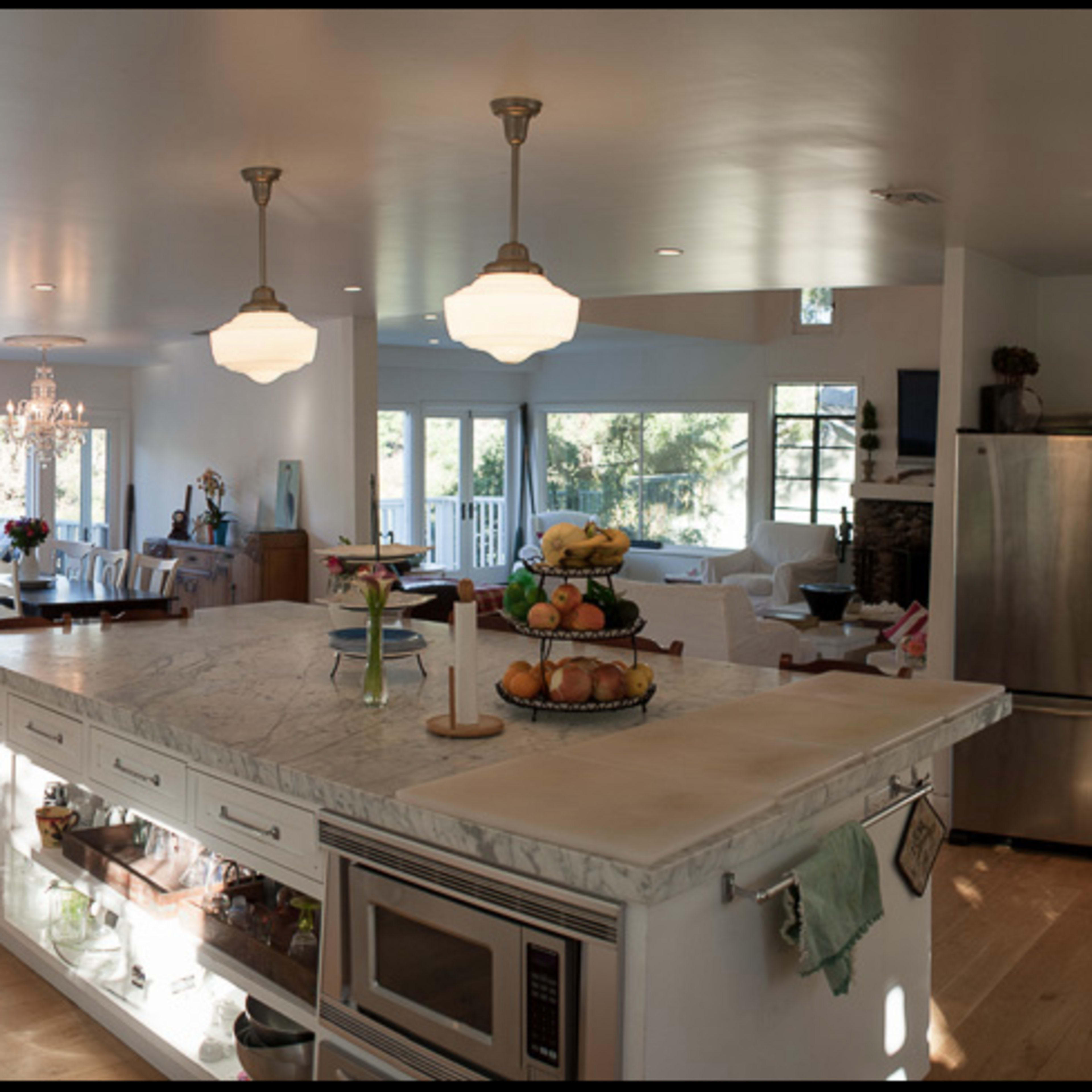 A spacious, modern kitchen with a central island, stainless steel appliances, and an open layout connecting to a dining area and outdoor views.
