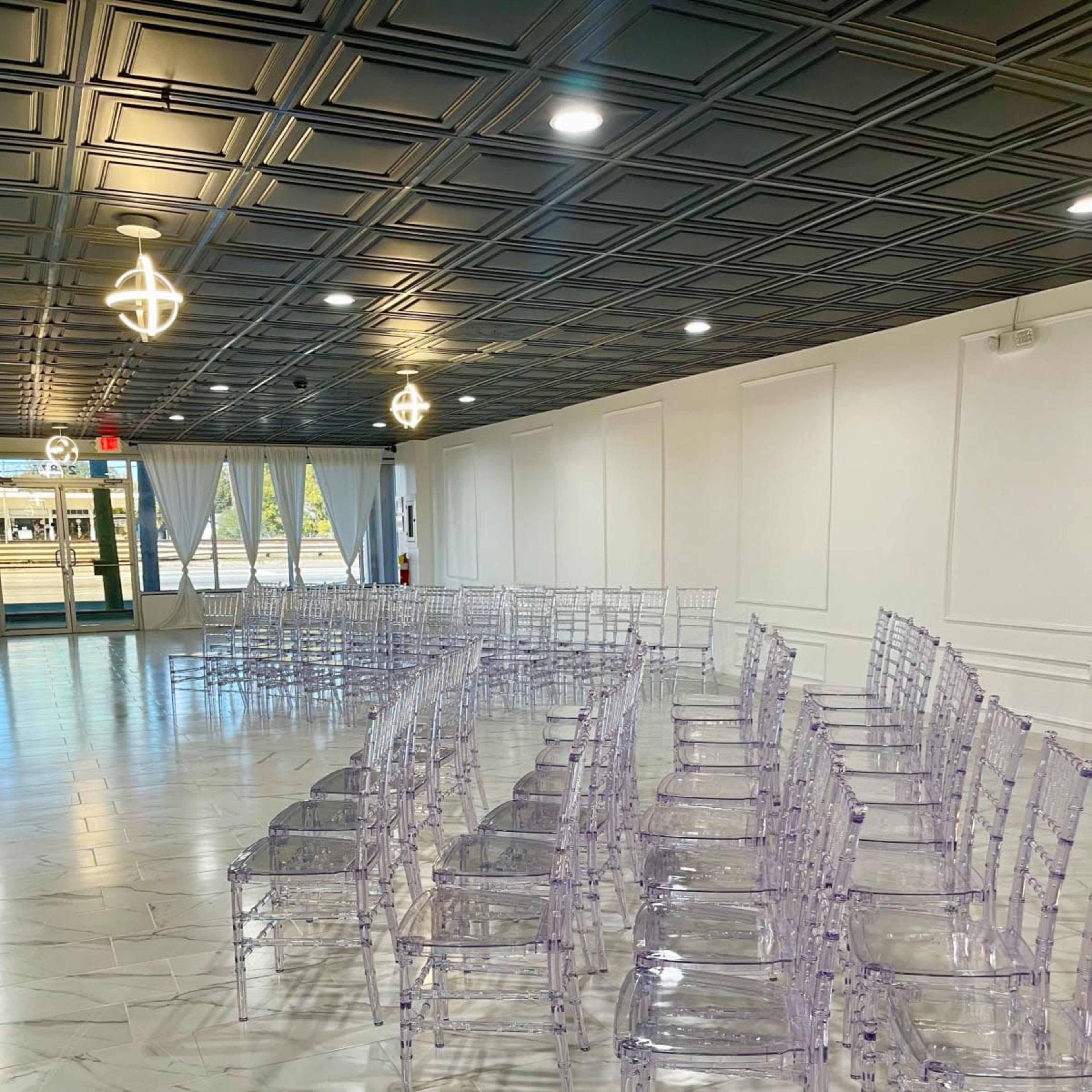 A row of transparent chairs is arranged in a neat formation on a marble floor in a well-lit indoor space.