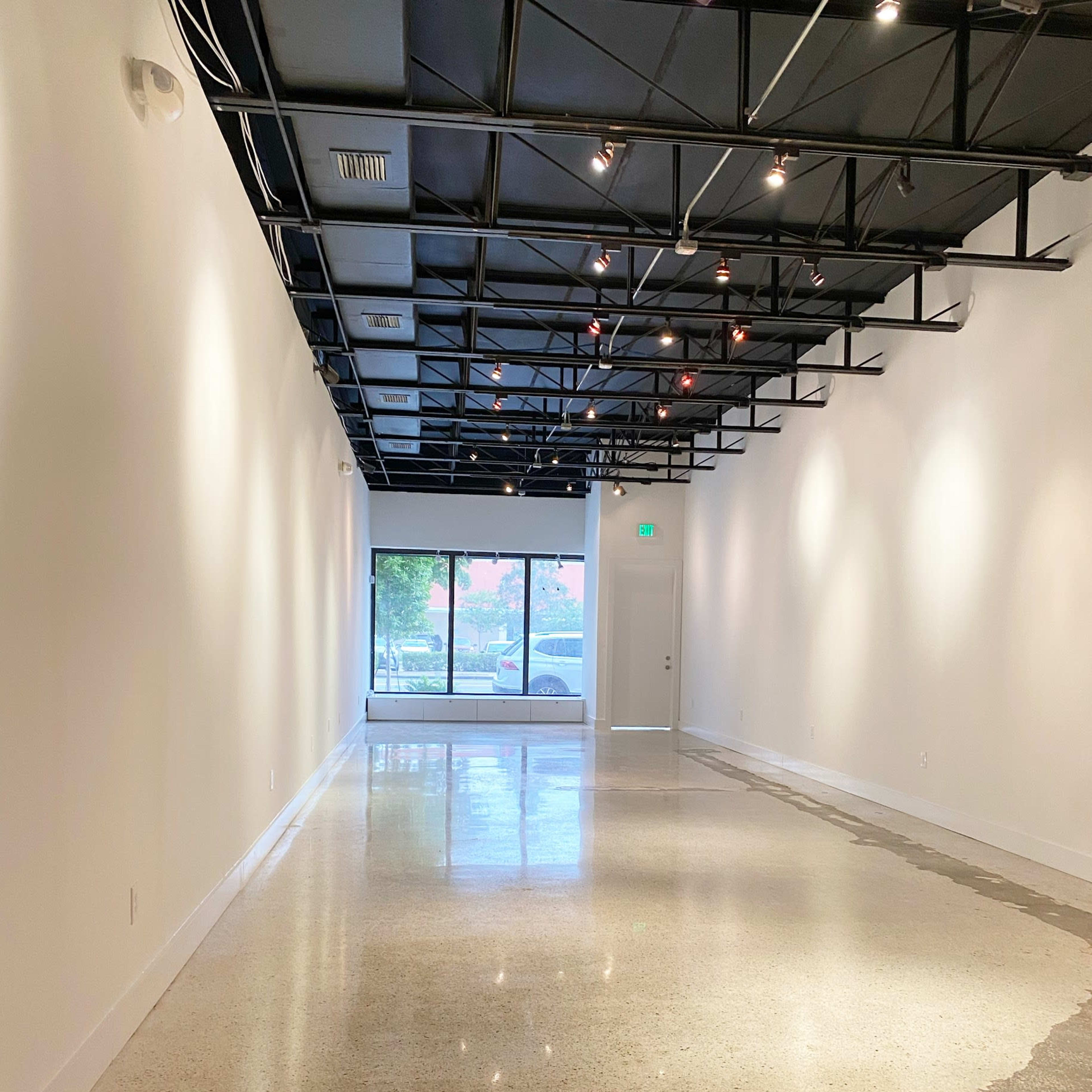 A spacious, empty room with polished concrete flooring and large windows at one end.