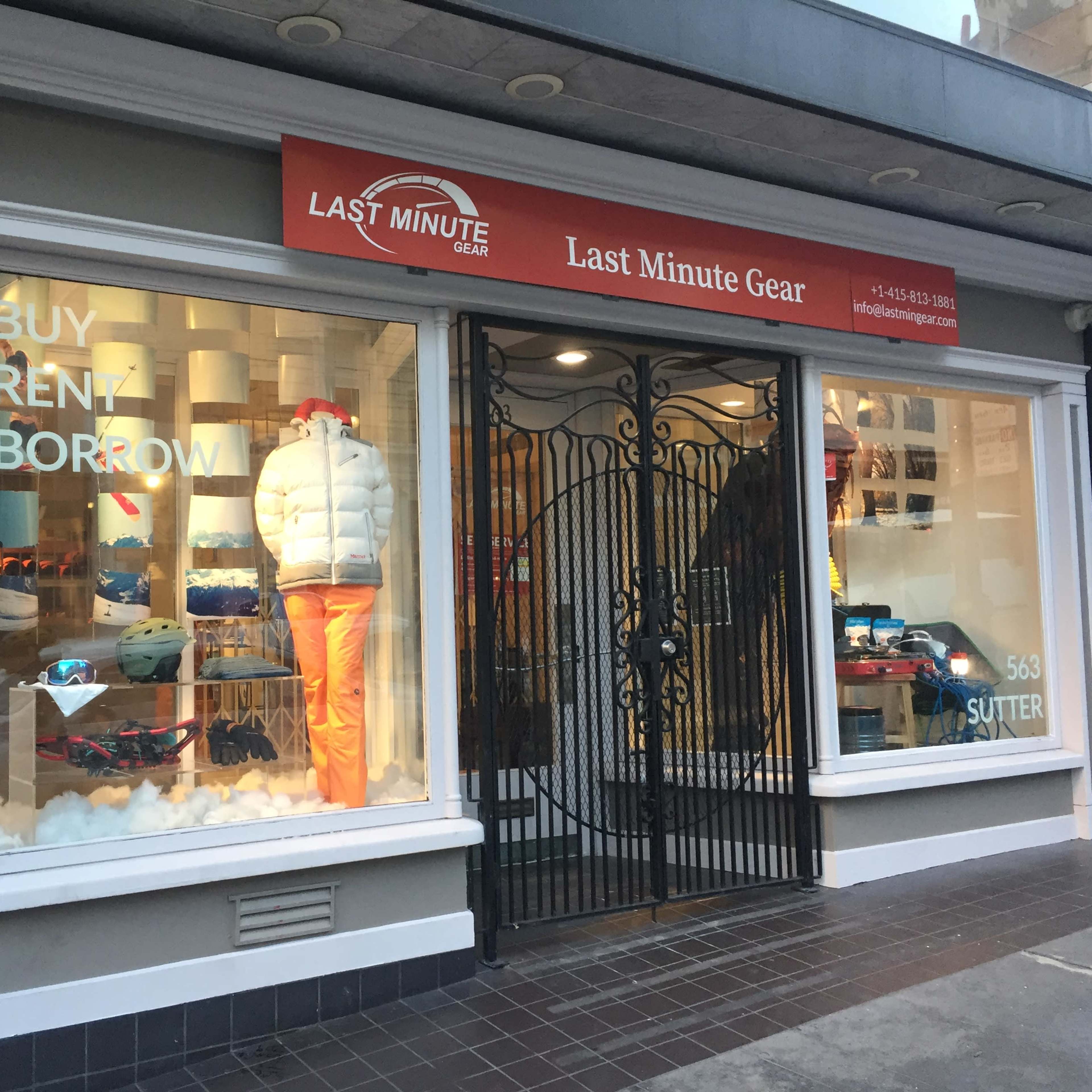 The storefront of "Last Minute Gear" features a window display showcasing winter apparel and equipment, with a sign highlighting options to buy, rent, or borrow.