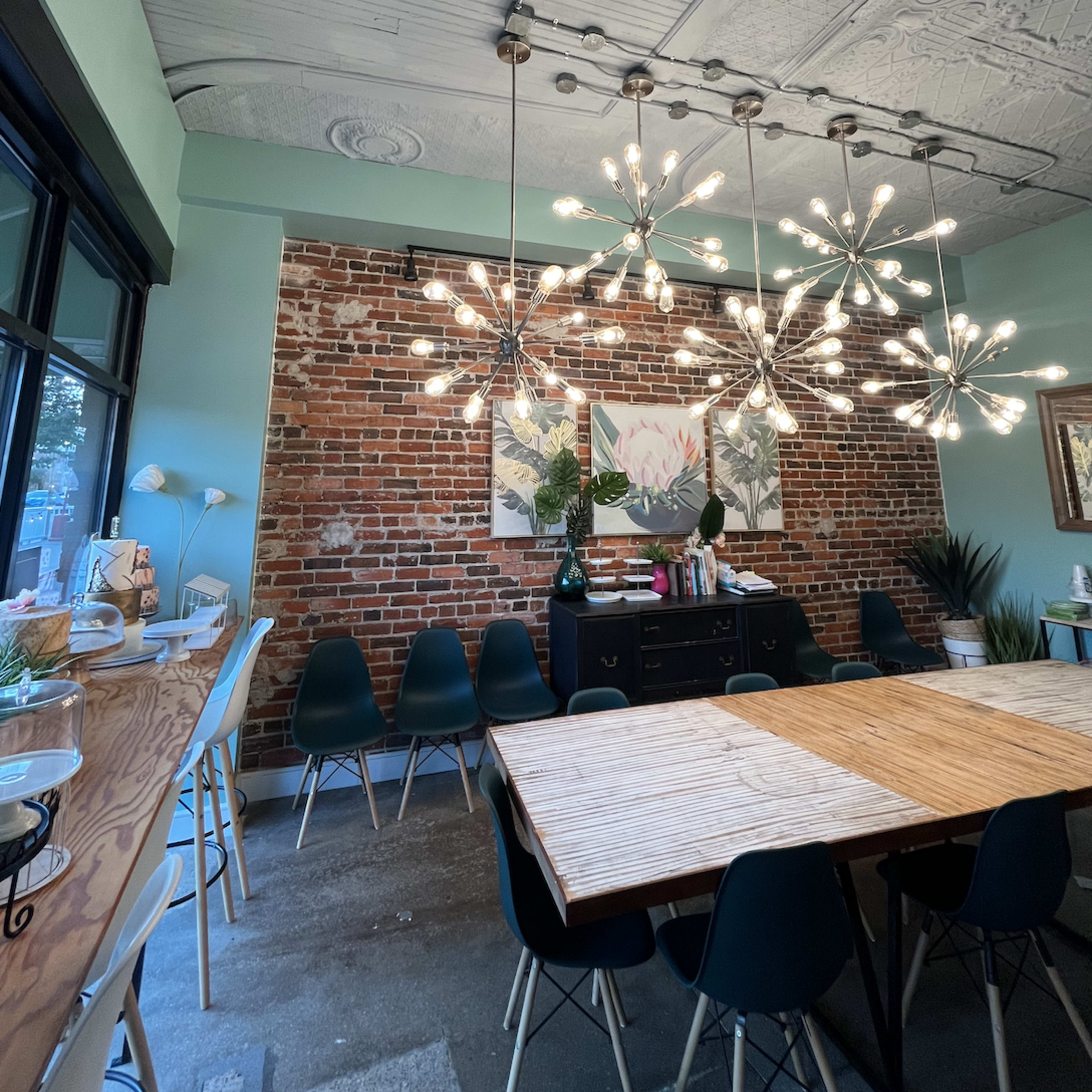 A modern room with exposed brick walls, a large wooden table at the center, and striking pendant lights hanging from the ceiling.