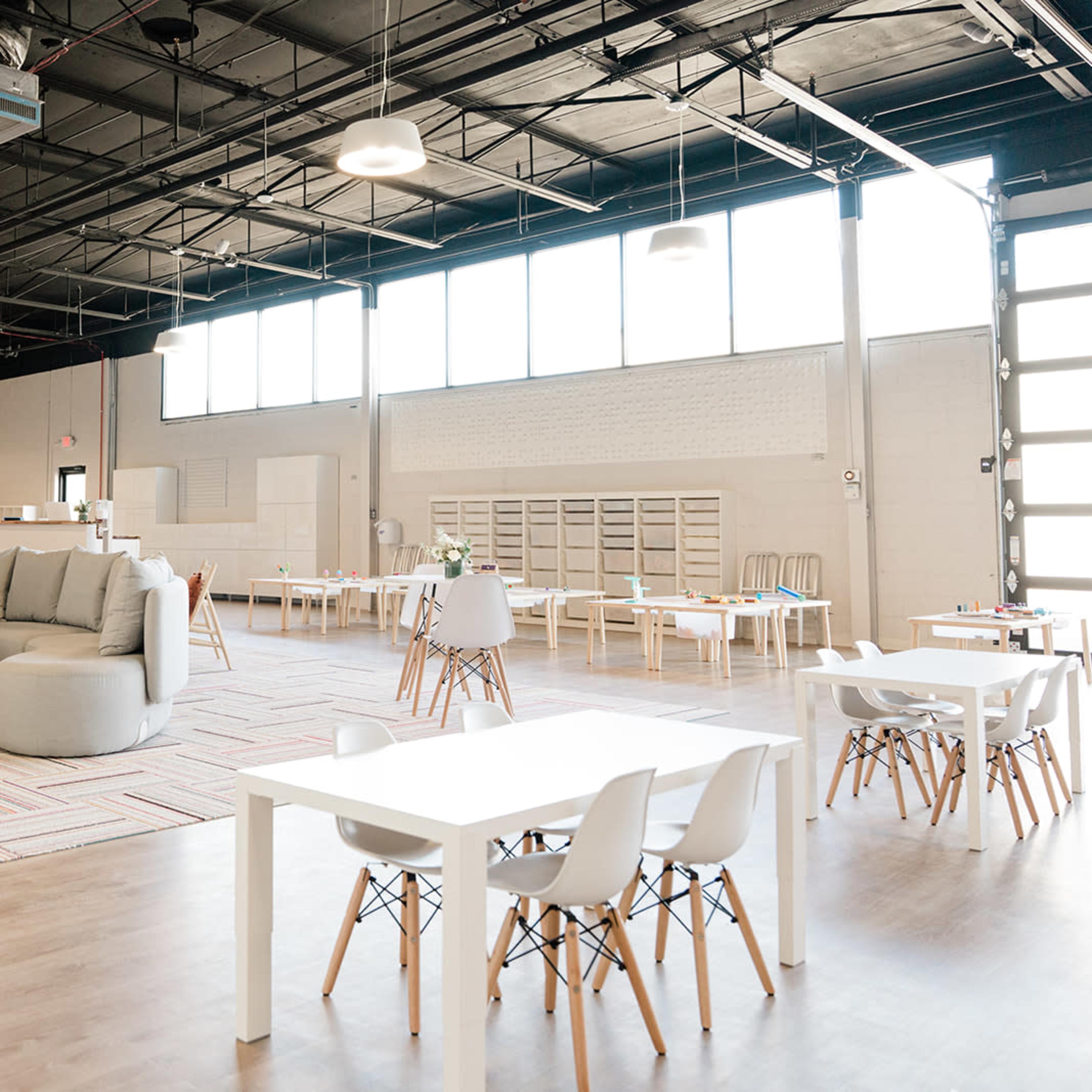 A spacious, well-lit interior of a modern workspace with various seating arrangements and tables.