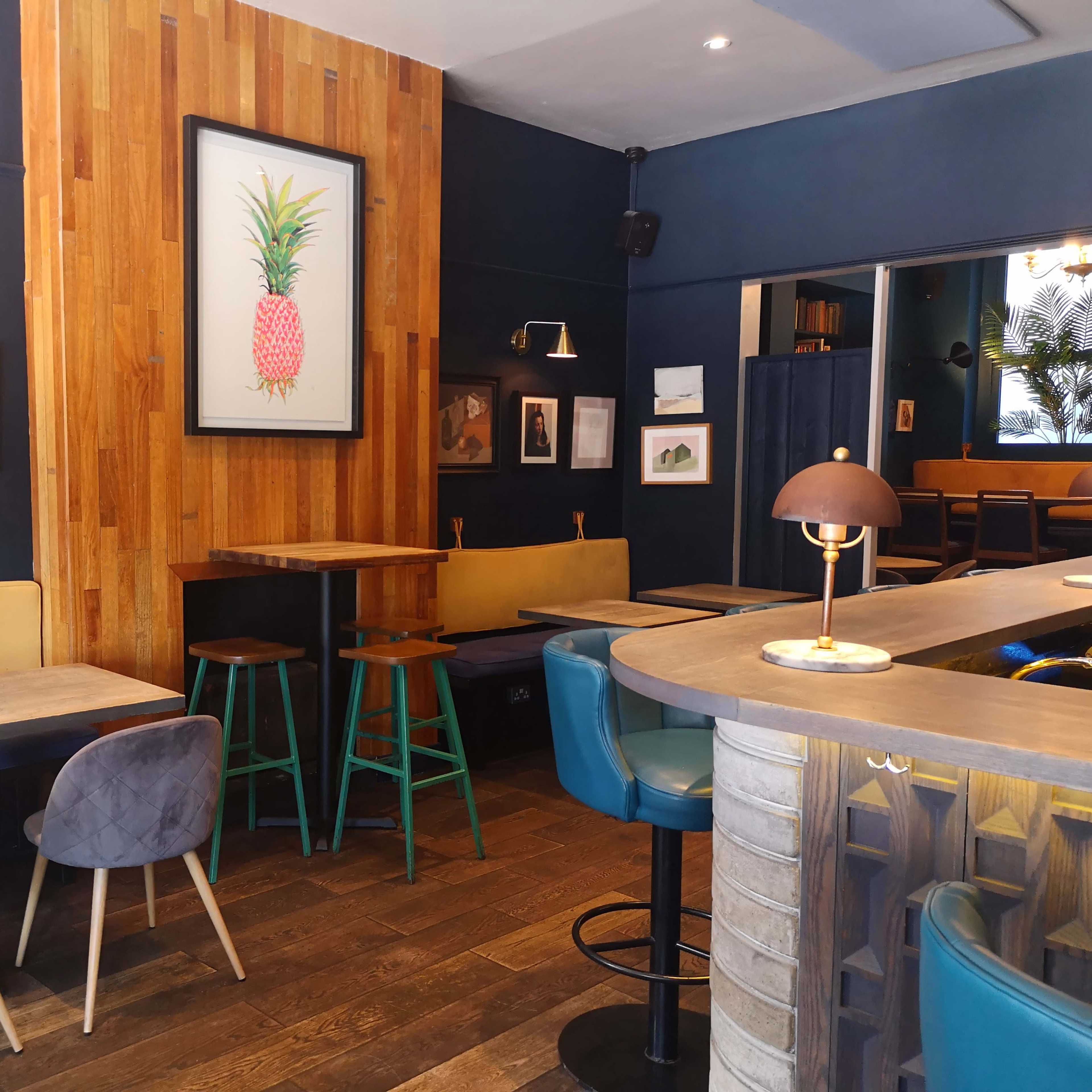 A cozy café interior with wooden accents, including tables and wall art depicting various subjects.
