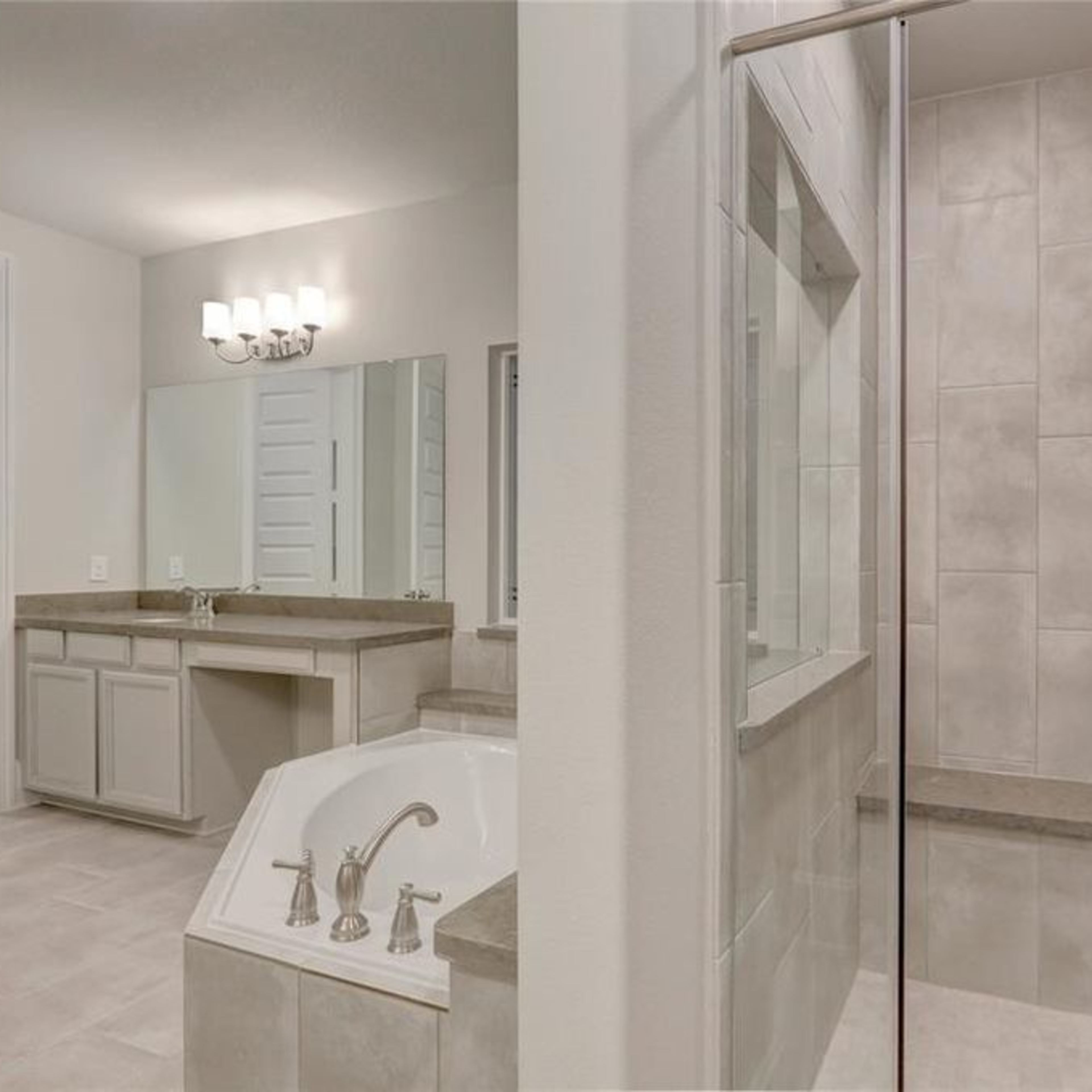 A modern bathroom featuring a glass-enclosed shower, a freestanding bathtub, dual sinks, and gray tile accents.