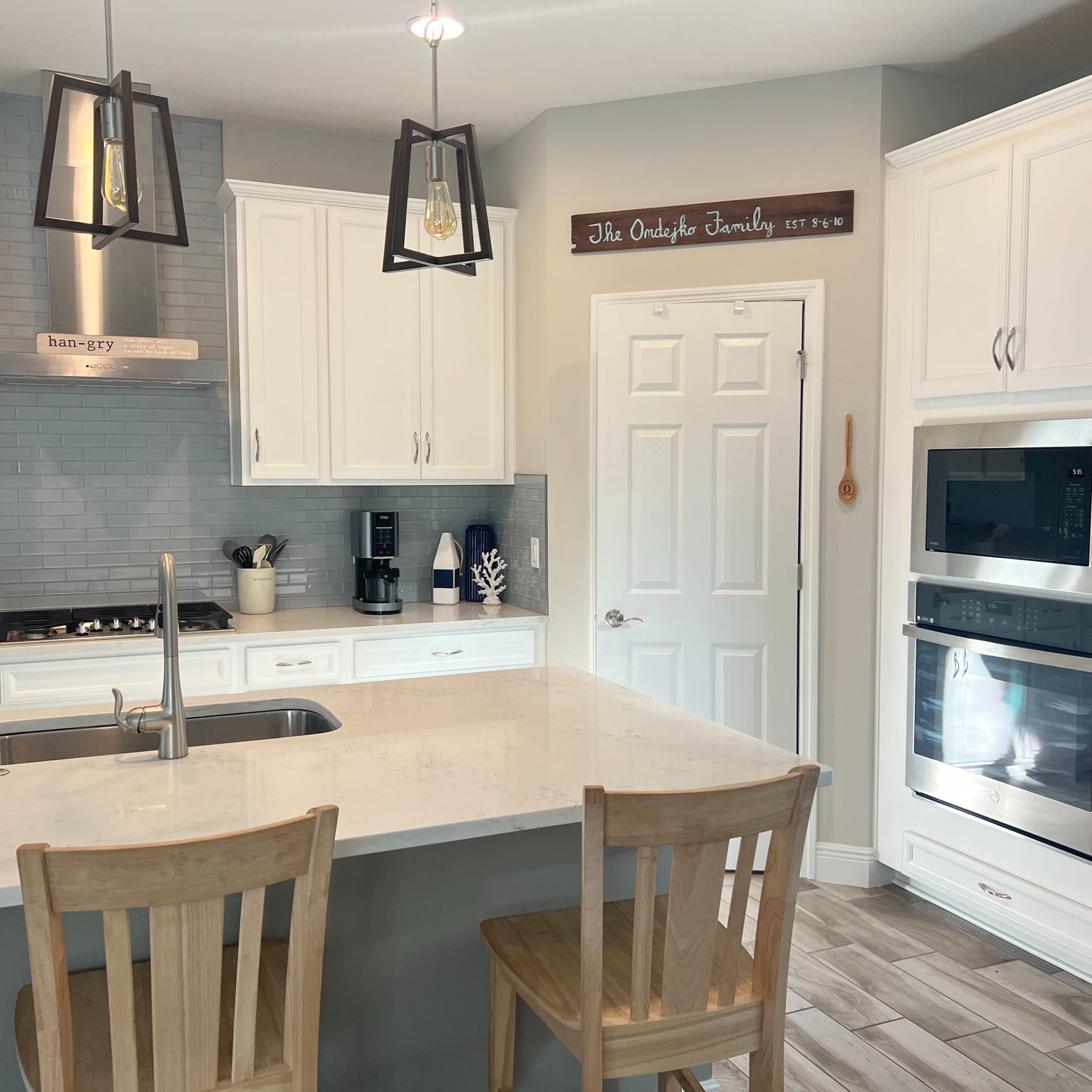 A modern kitchen features white cabinetry, stainless steel appliances, and a large island with seating.