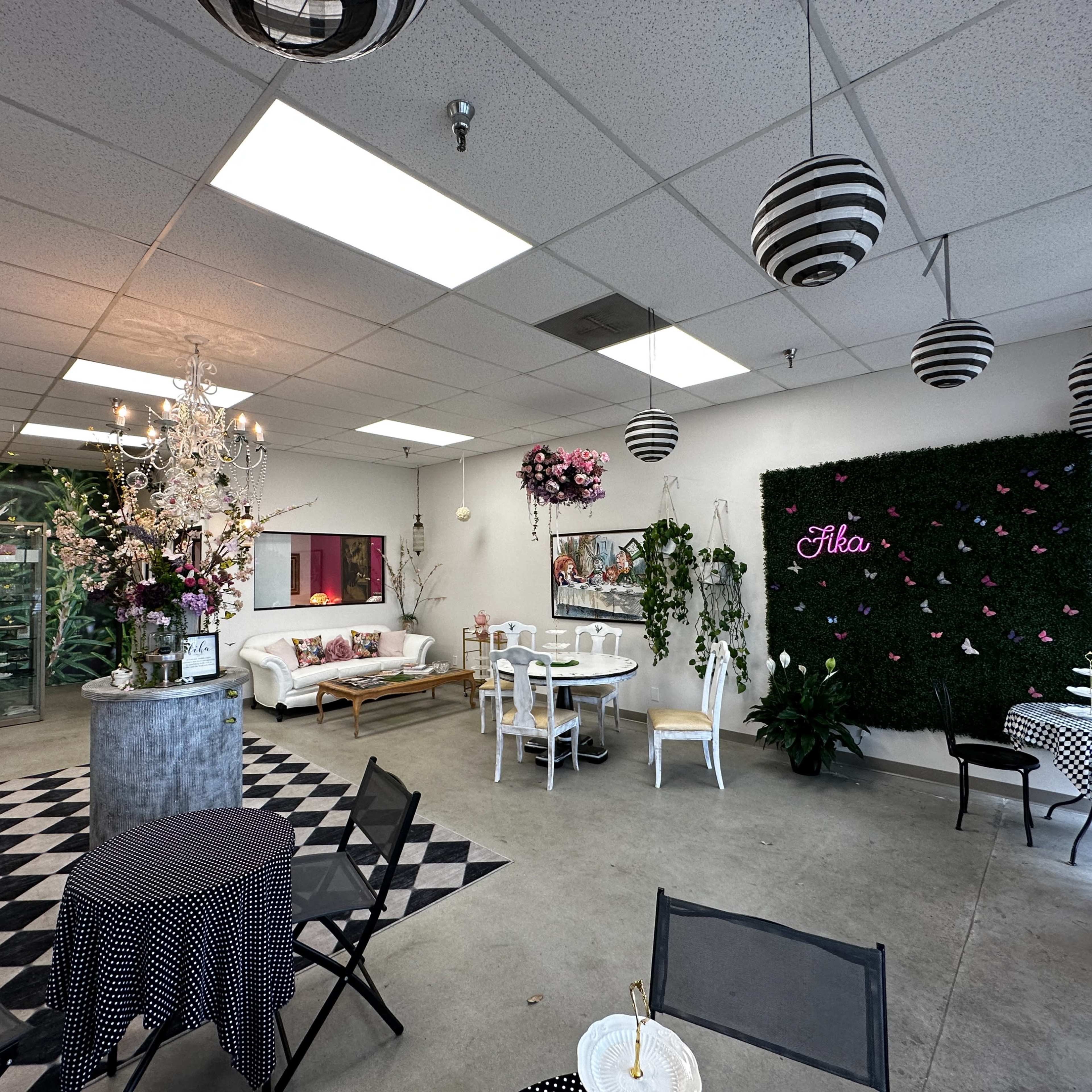 A spacious, decorated interior with seating arrangements, greenery, and decorative elements like a chandelier and wall art.