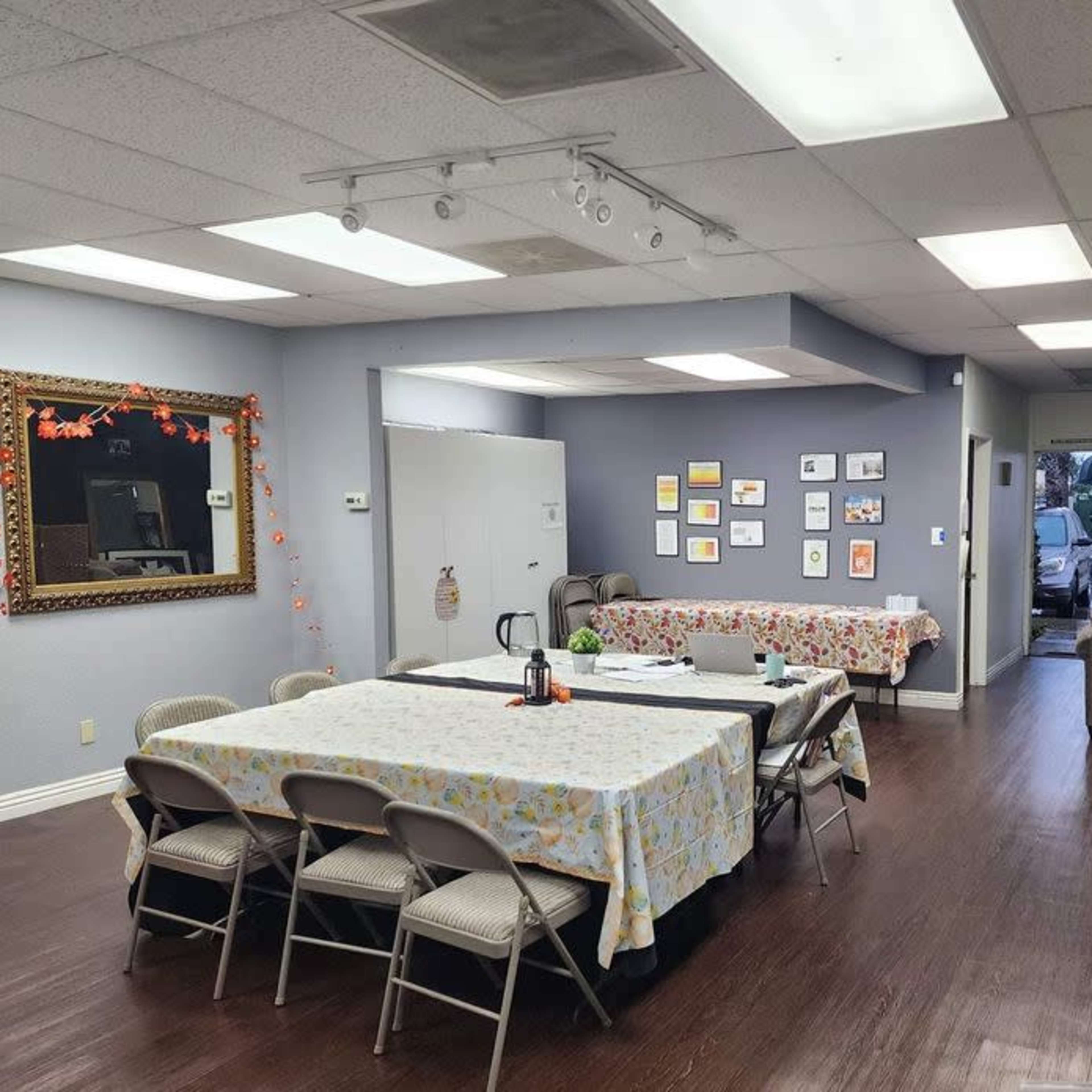 A spacious room with tables covered in cloths, framed artwork on the walls, and packing boxes stacked in one corner.
