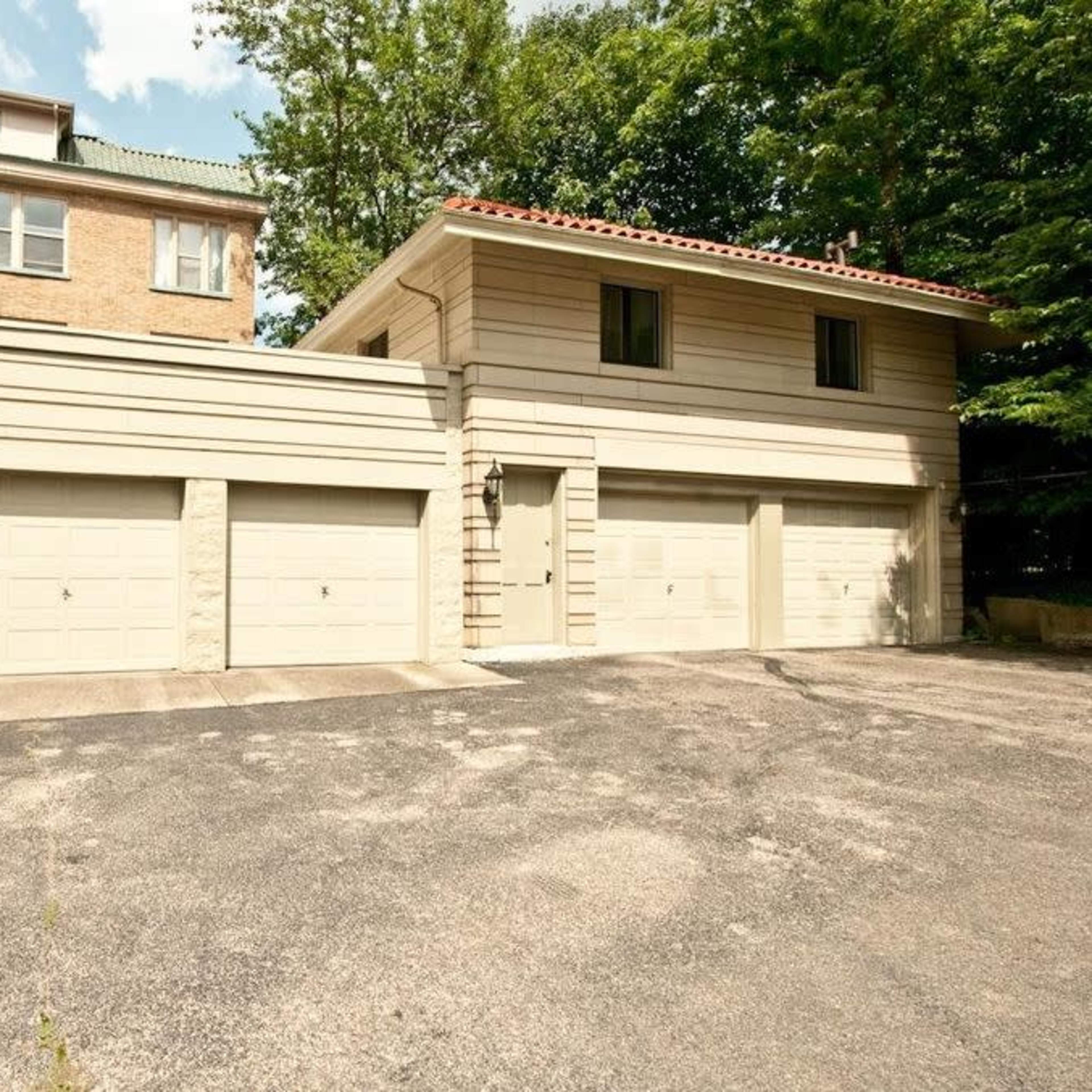 A two-car garage attached to a building with a light-colored exterior and a small window on the upper floor.