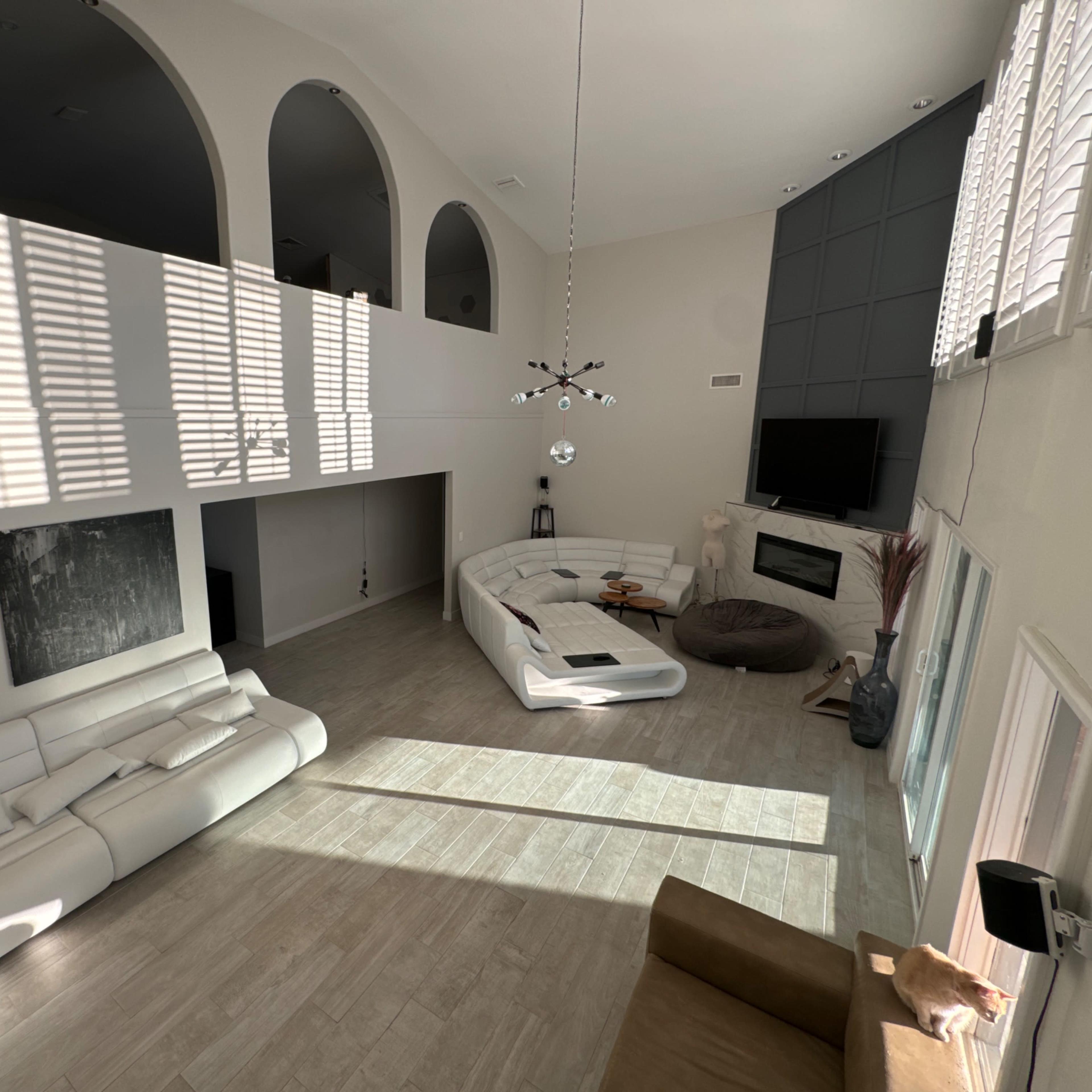 A spacious living room with modern furniture, large windows, and distinct architectural features such as arches and a fireplace.