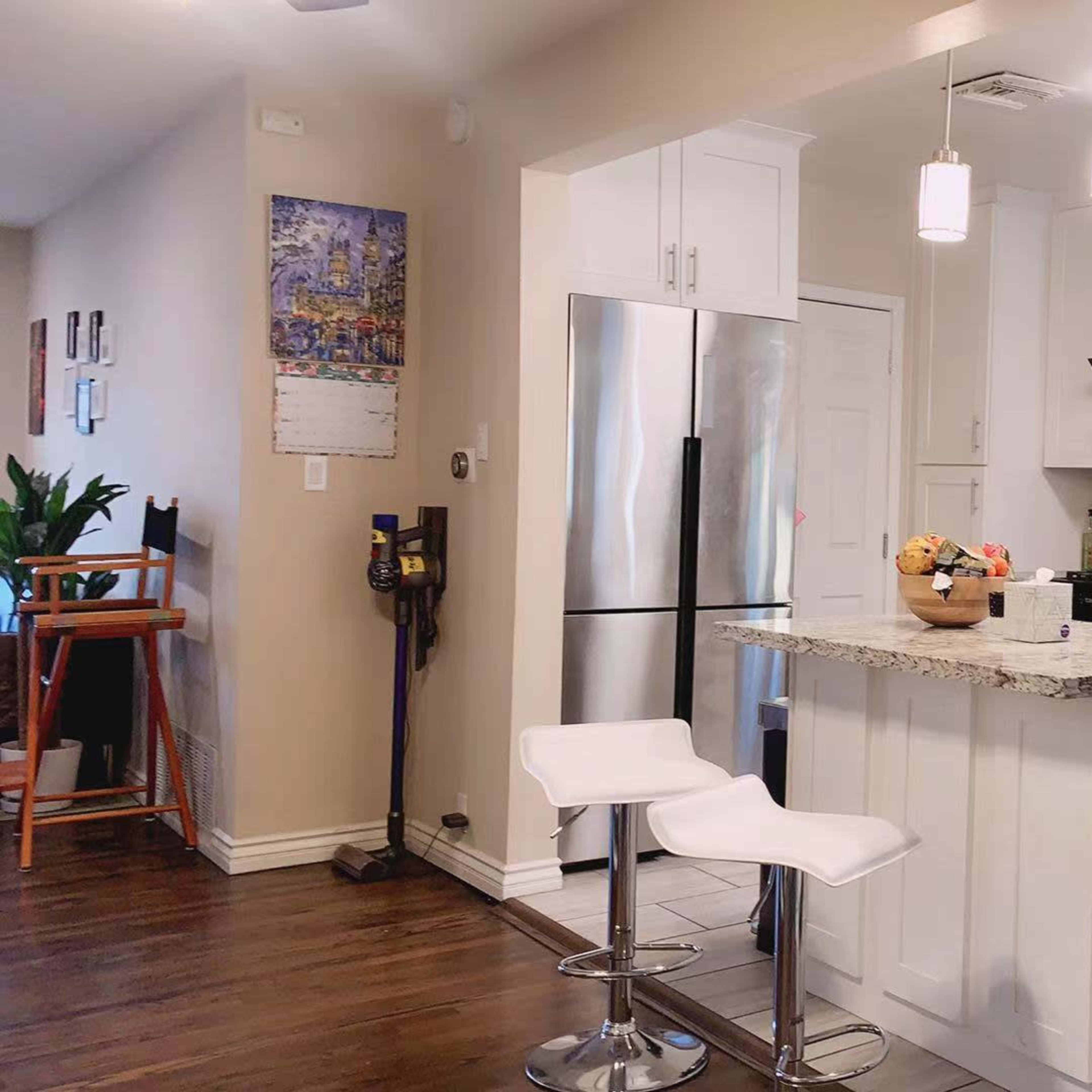 A modern kitchen features white cabinetry, stainless steel appliances, a granite countertop, and seating at a bar-style island.