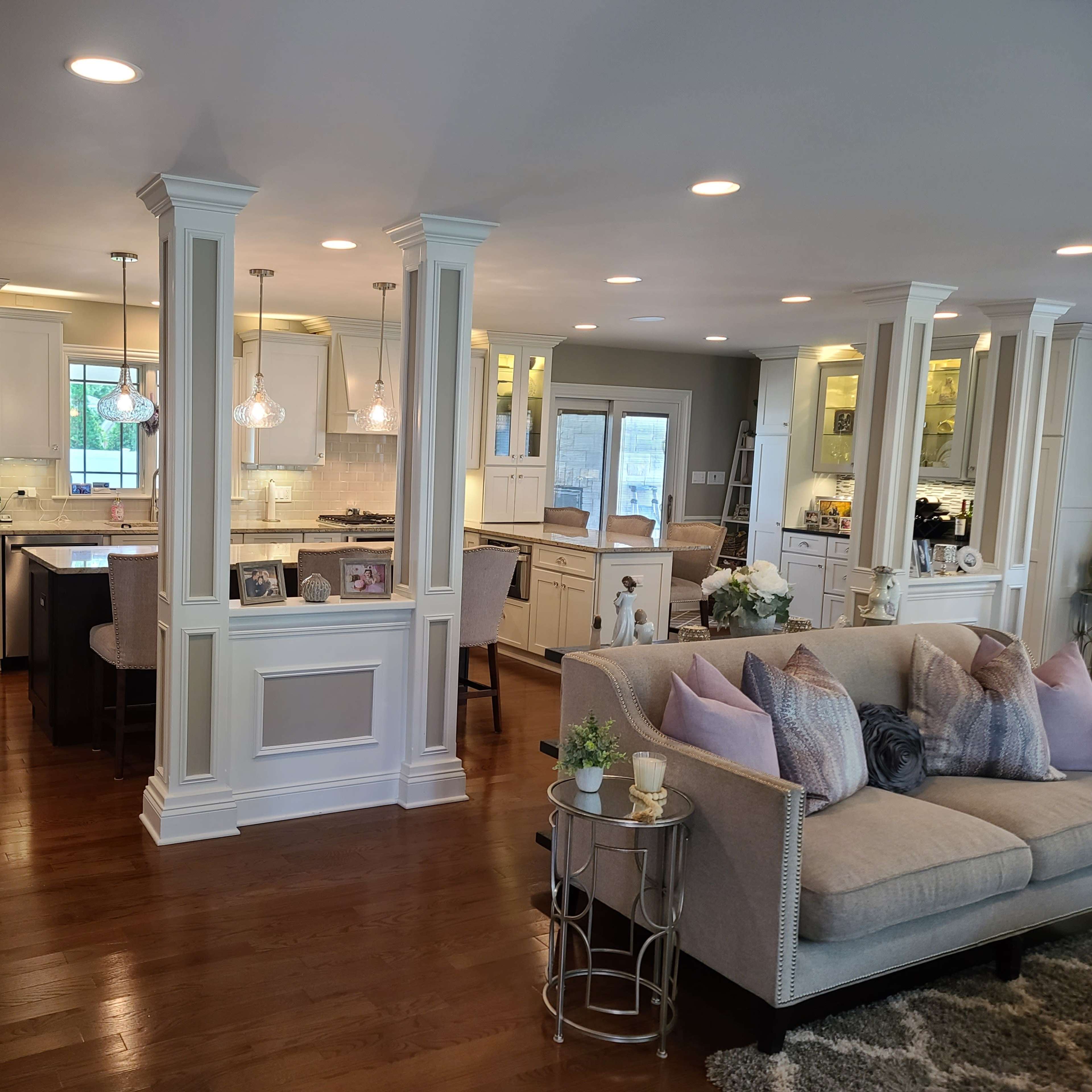 A spacious open-concept living area with a kitchen, dining area, and seating arrangement, featuring wooden floors and light-colored cabinetry.