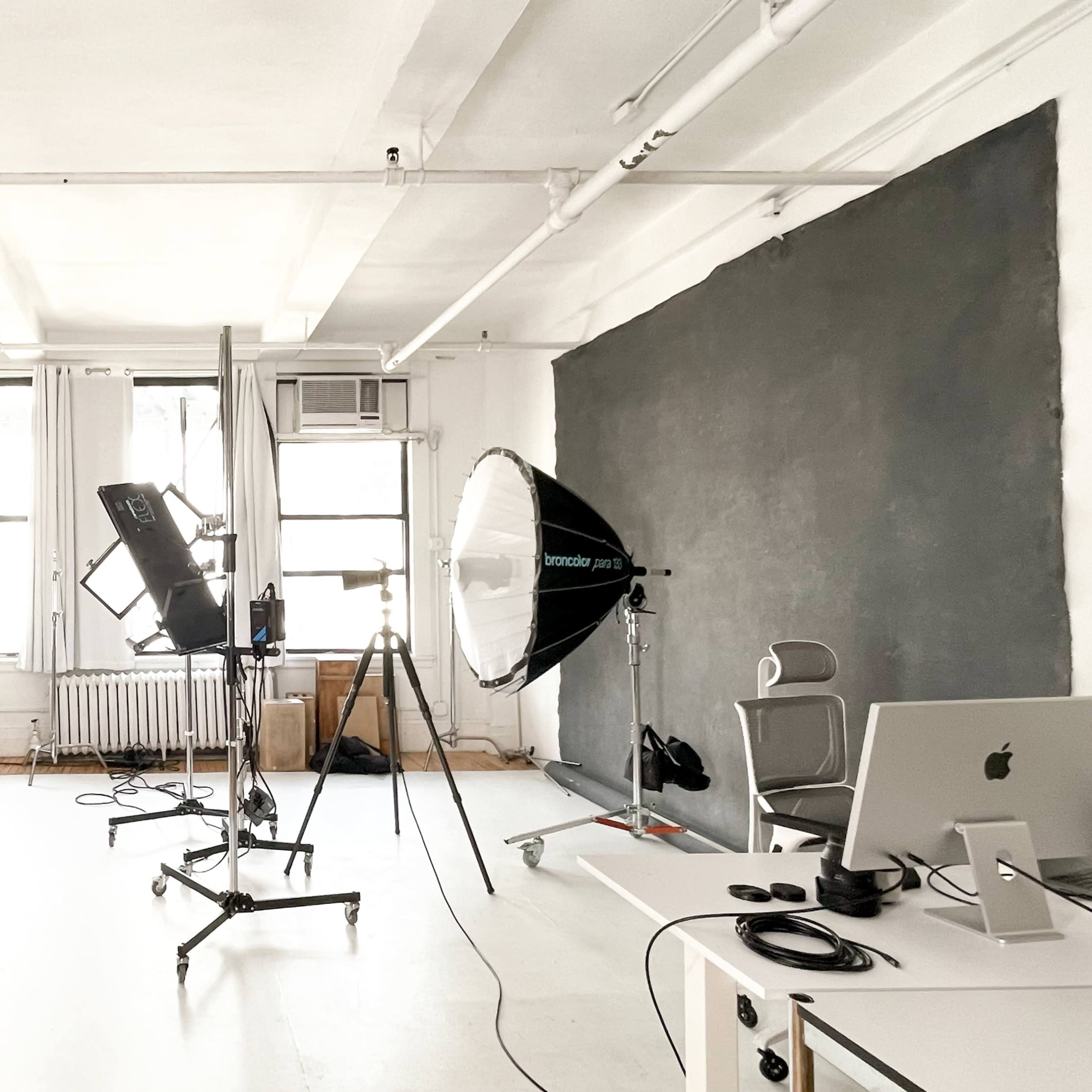 A photography studio equipped with lighting setups, a backdrop, and a workstation.