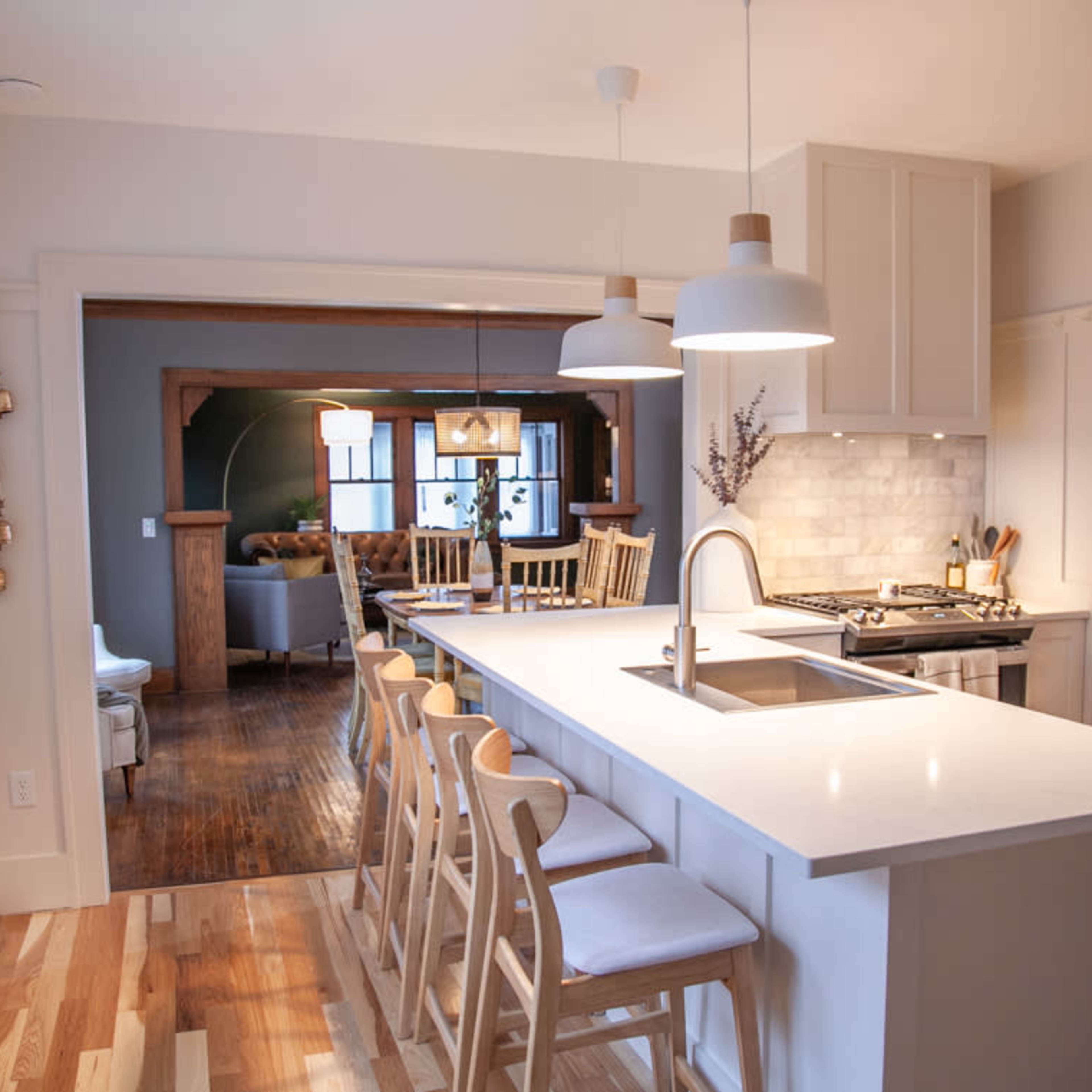 A modern kitchen features a central island with seating and a view into a cozy living area beyond.