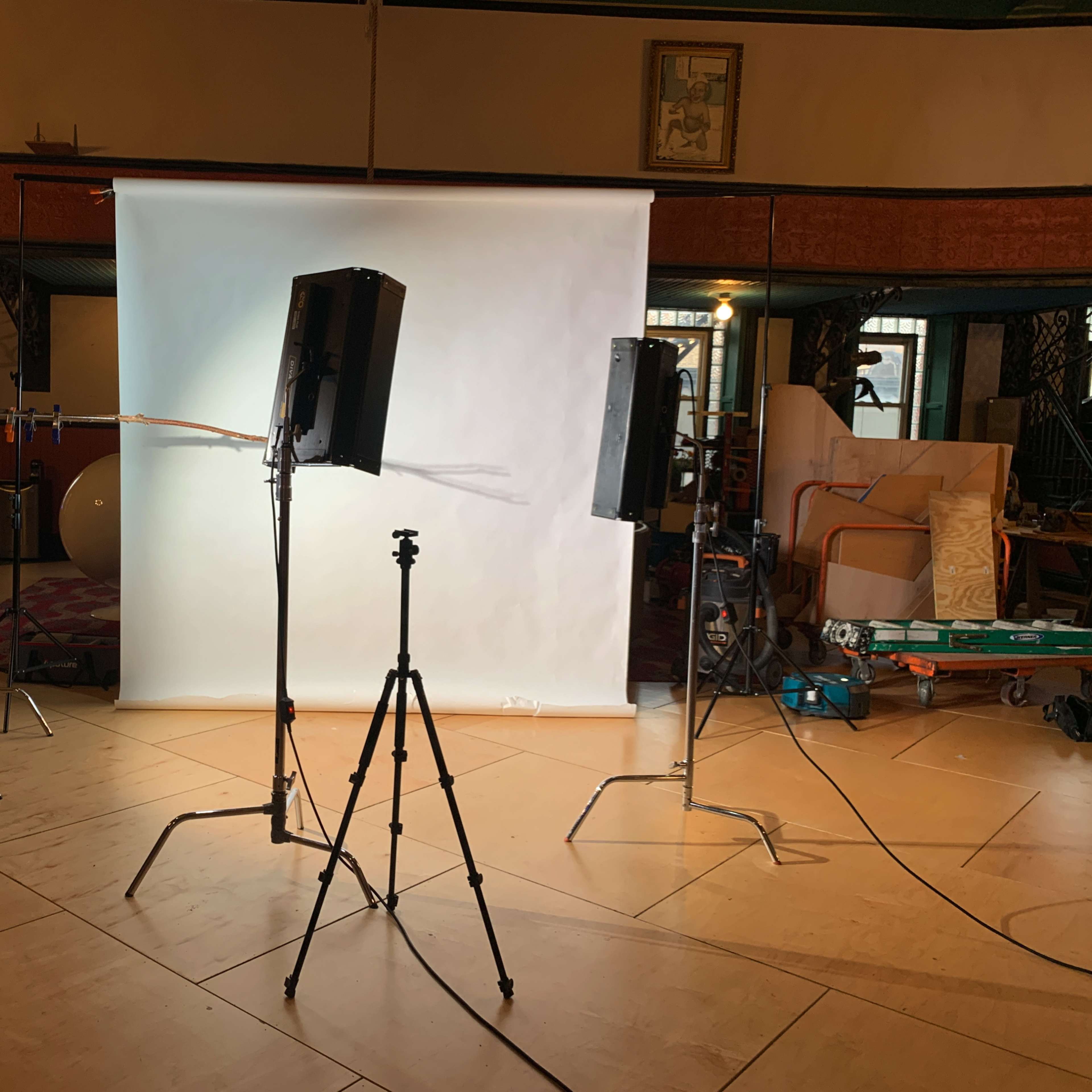 A photography setup is arranged with lights and a backdrop in a studio space.