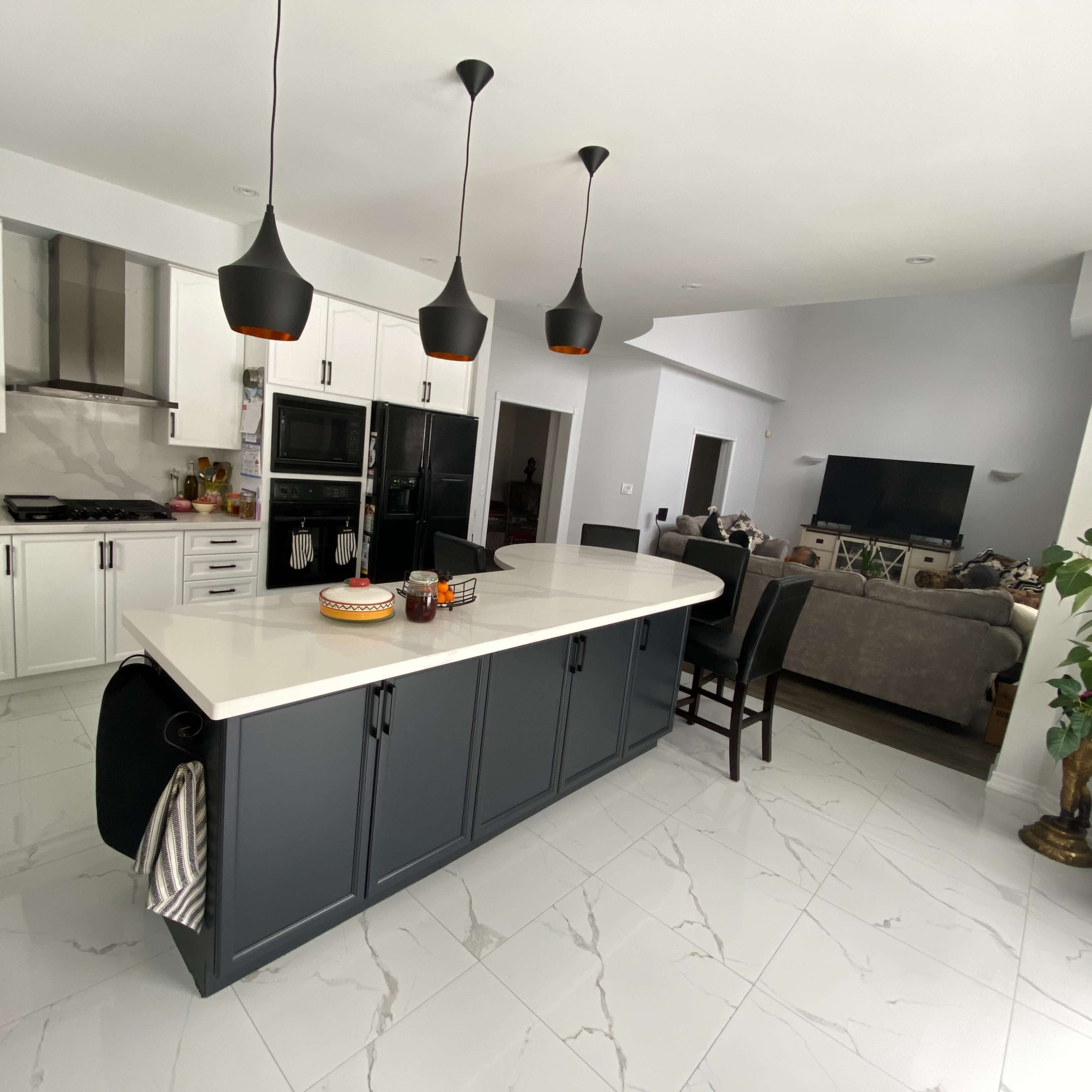 The kitchen features a large island with black cabinetry, white countertops, and three pendant lights hanging above.