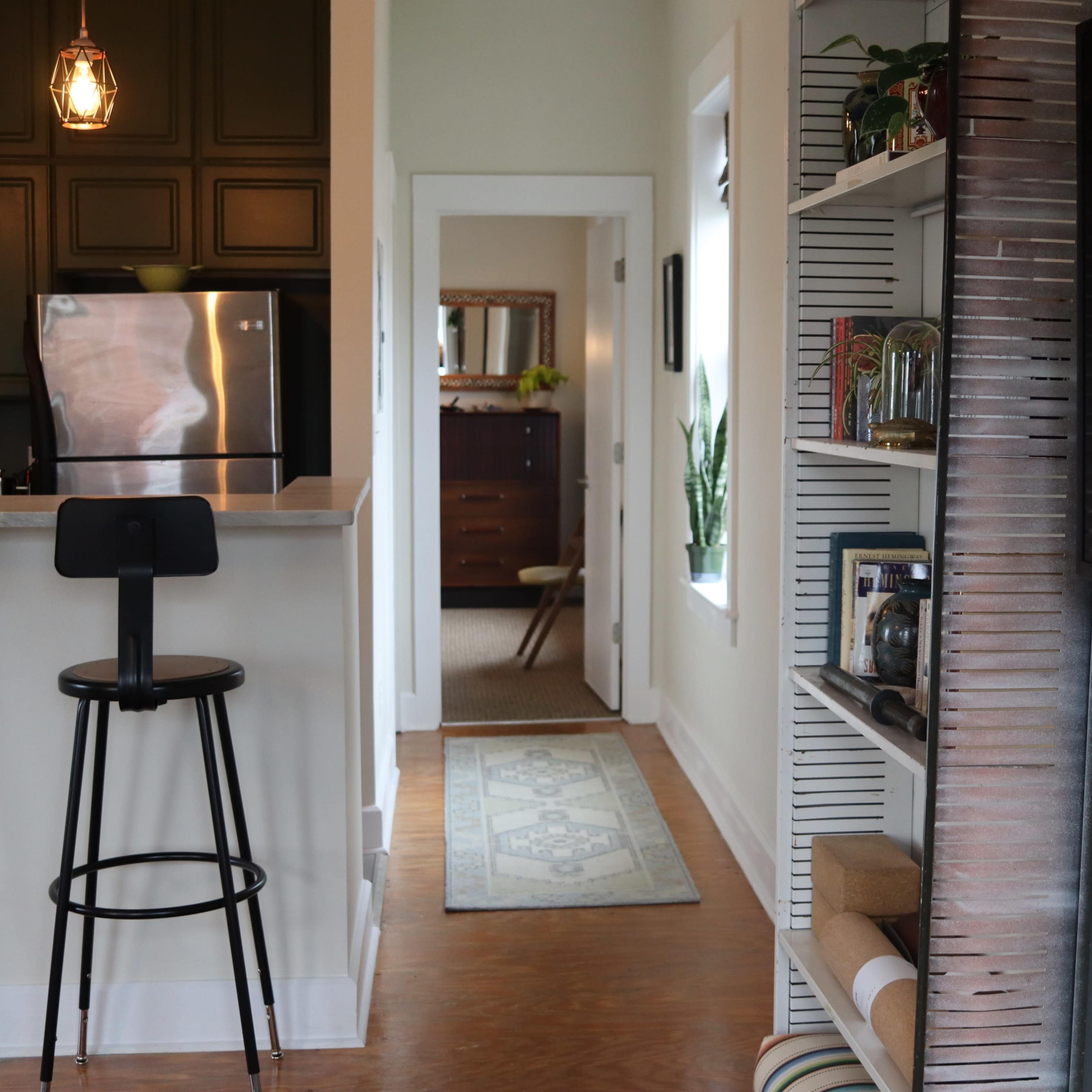 A spacious room with exposed brick walls, large mirrors, and a plant in the corner.