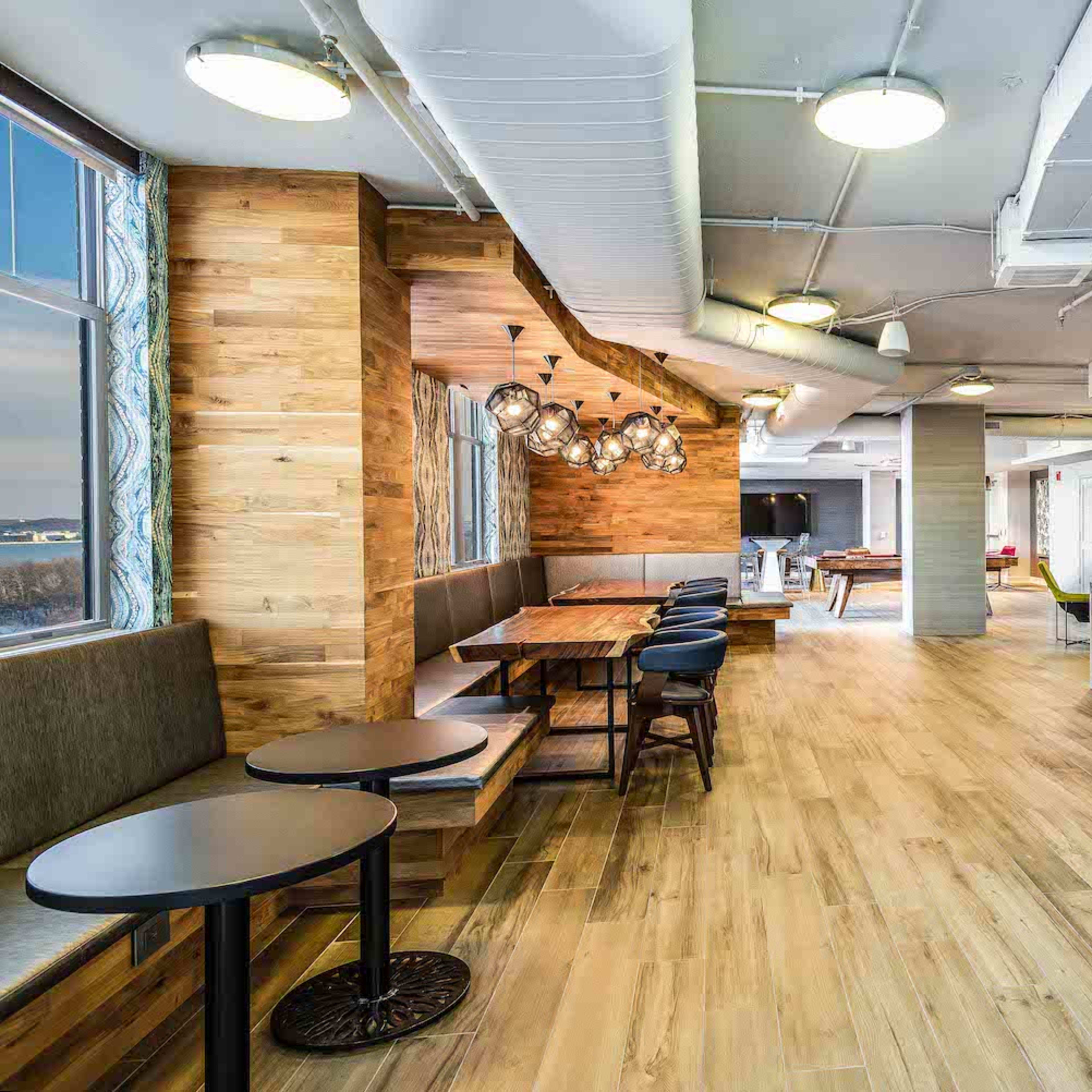 A modern communal kitchen and dining area with wooden accents, sleek surfaces, and both table and seating arrangements.