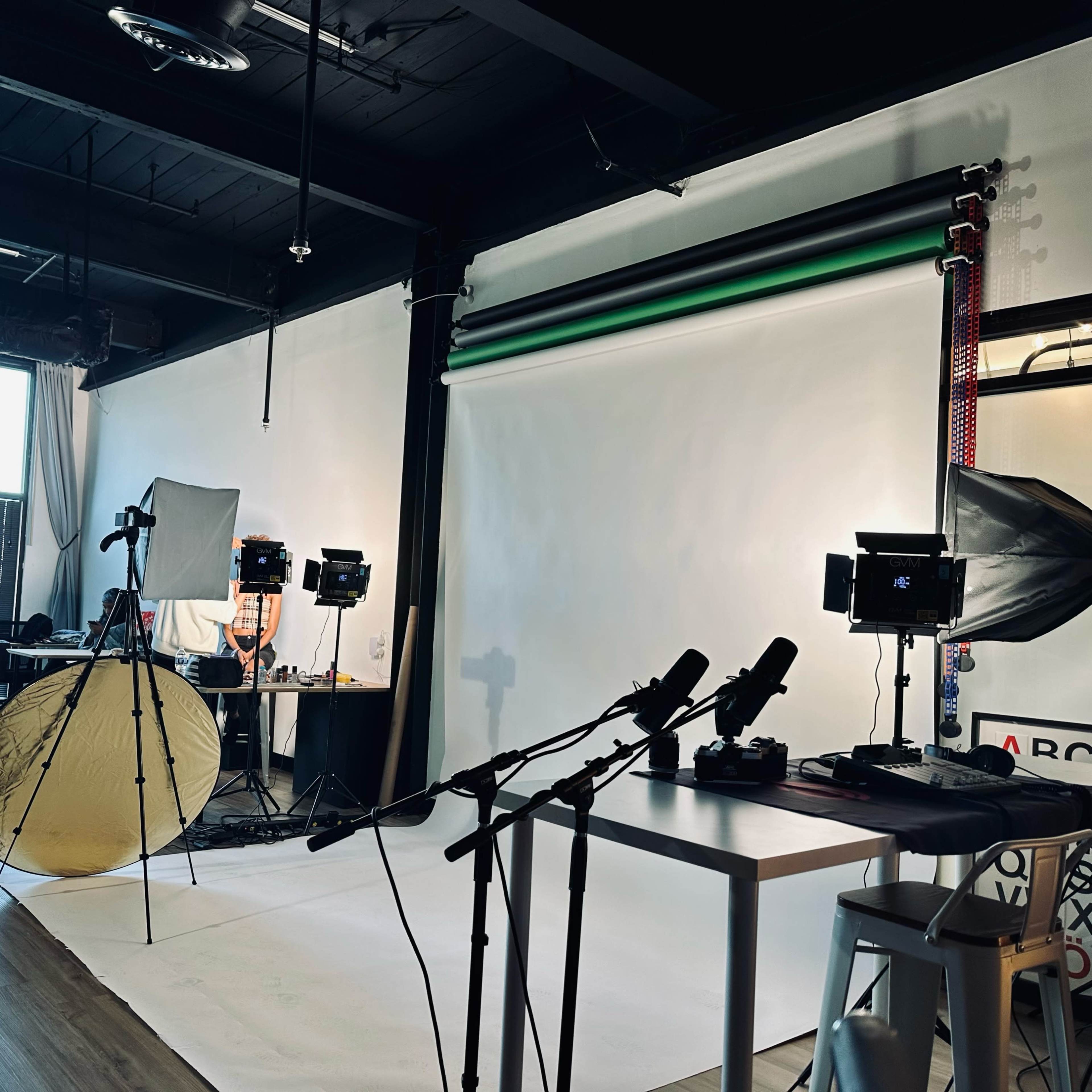 A photography studio is set up with a backdrop, lighting equipment, and audio microphones arranged for a shoot.