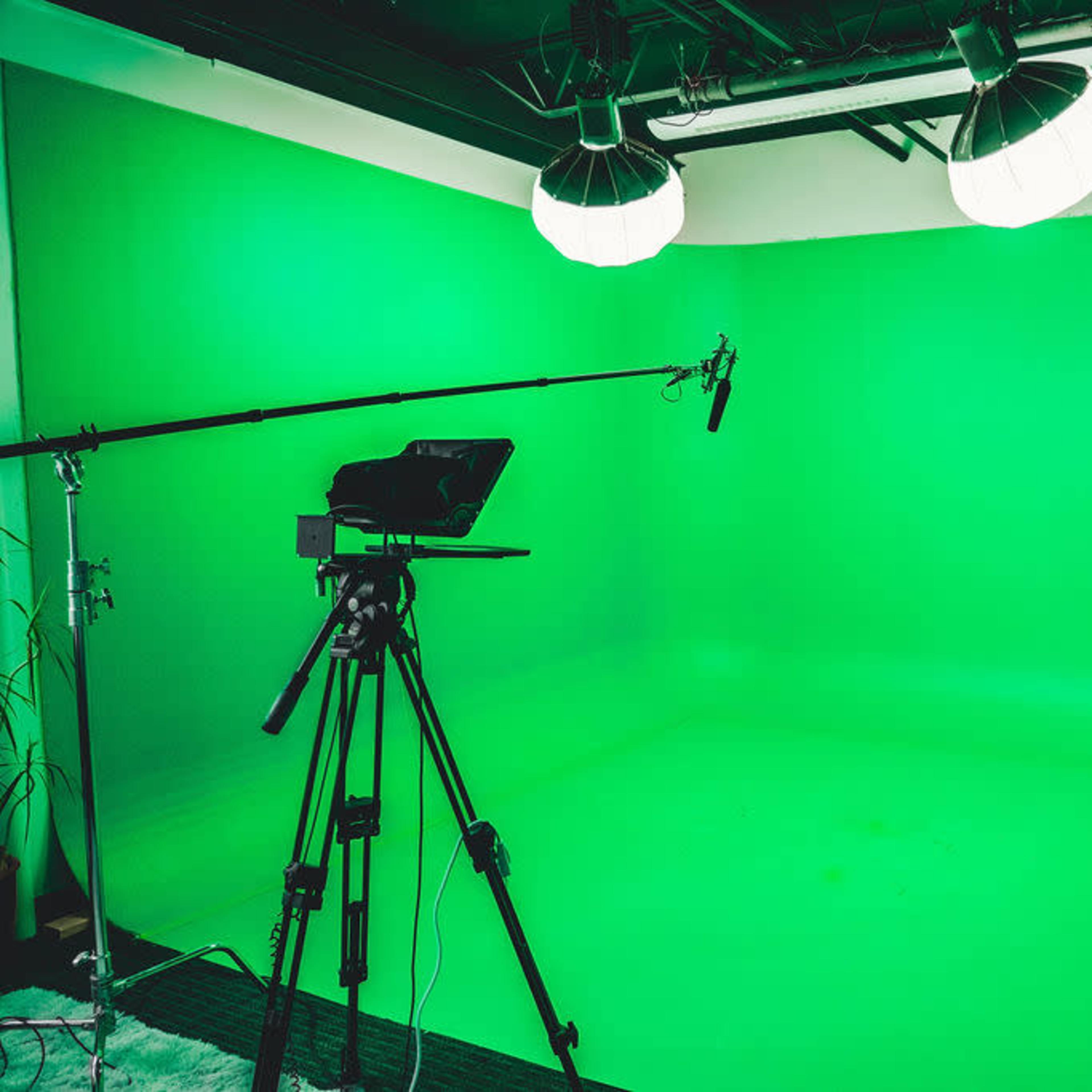 A green screen studio with a camera, microphone, and lighting setup.