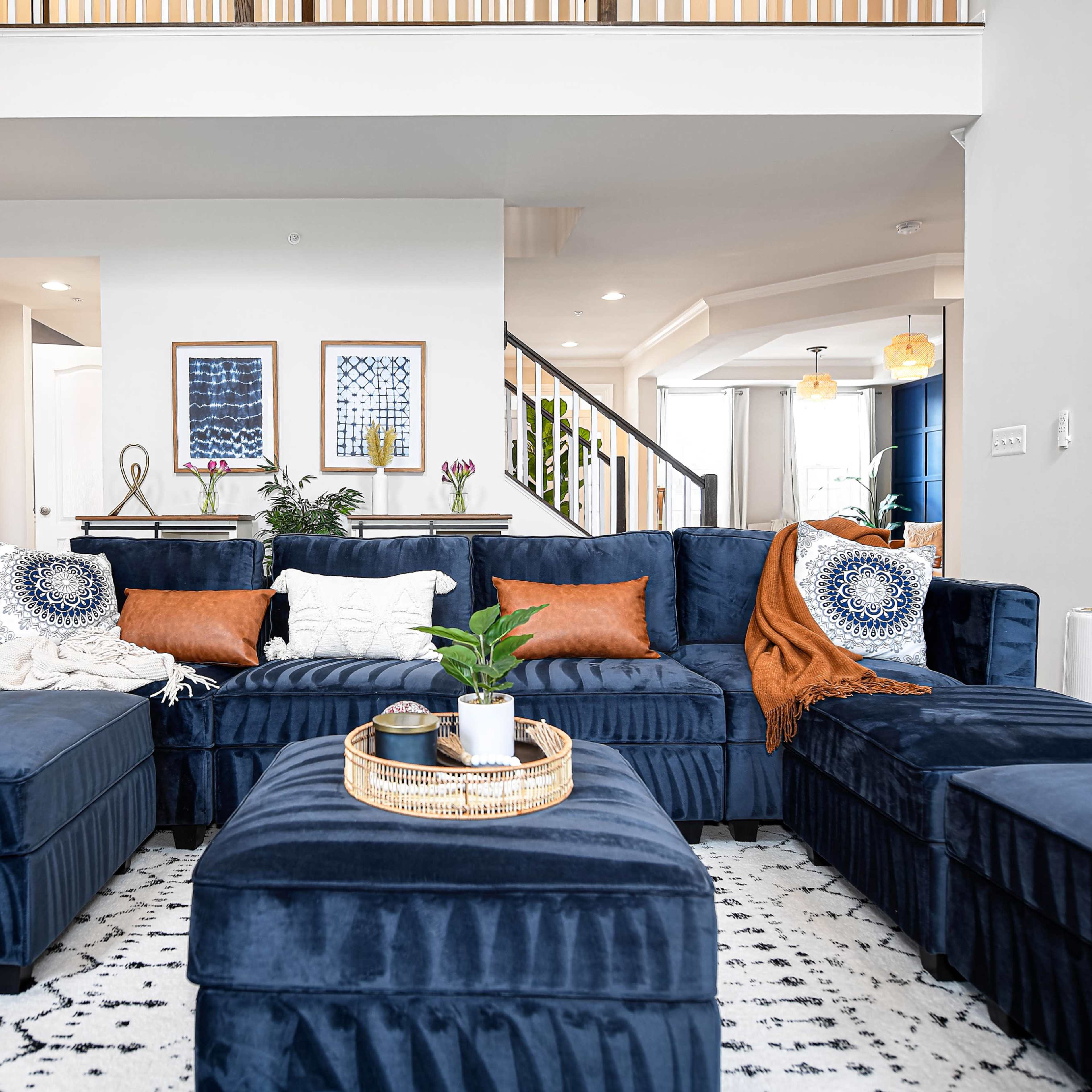 A modern living room with a dark blue sectional sofa arranged around a round coffee table on a patterned rug.