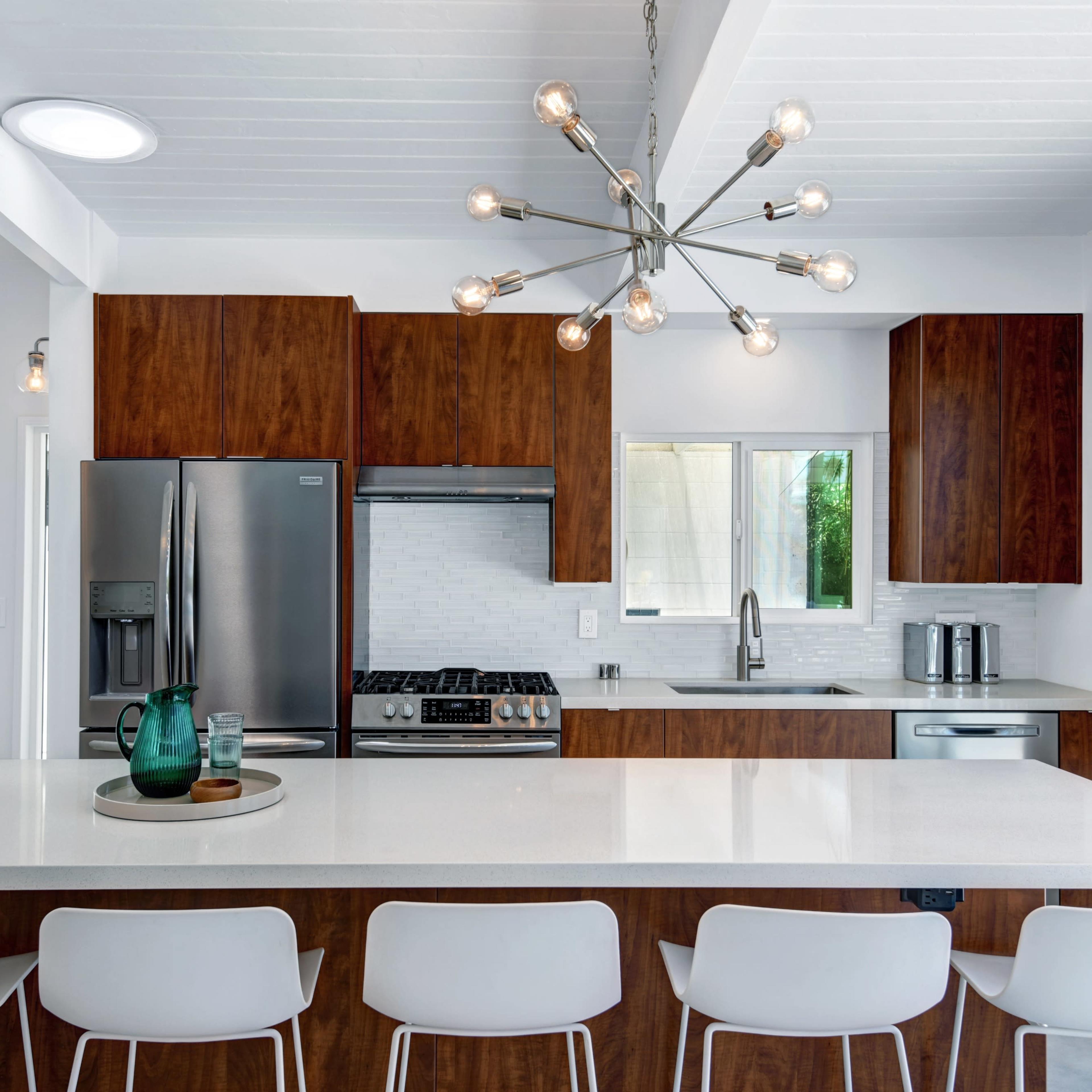 A modern kitchen features a large island with seating, stainless steel appliances, and wooden cabinetry.