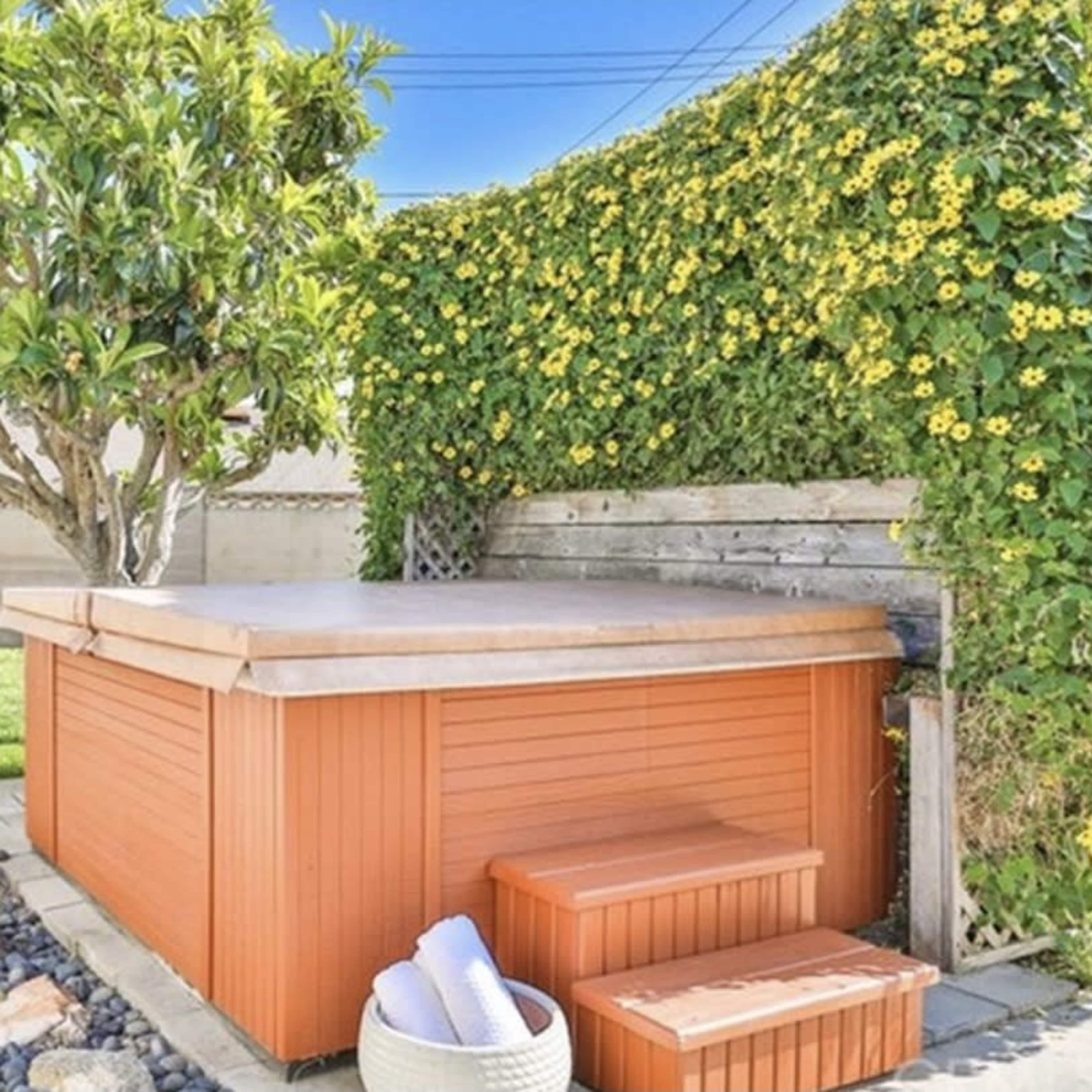 A hot tub surrounded by lush greenery and a neatly landscaped yard.