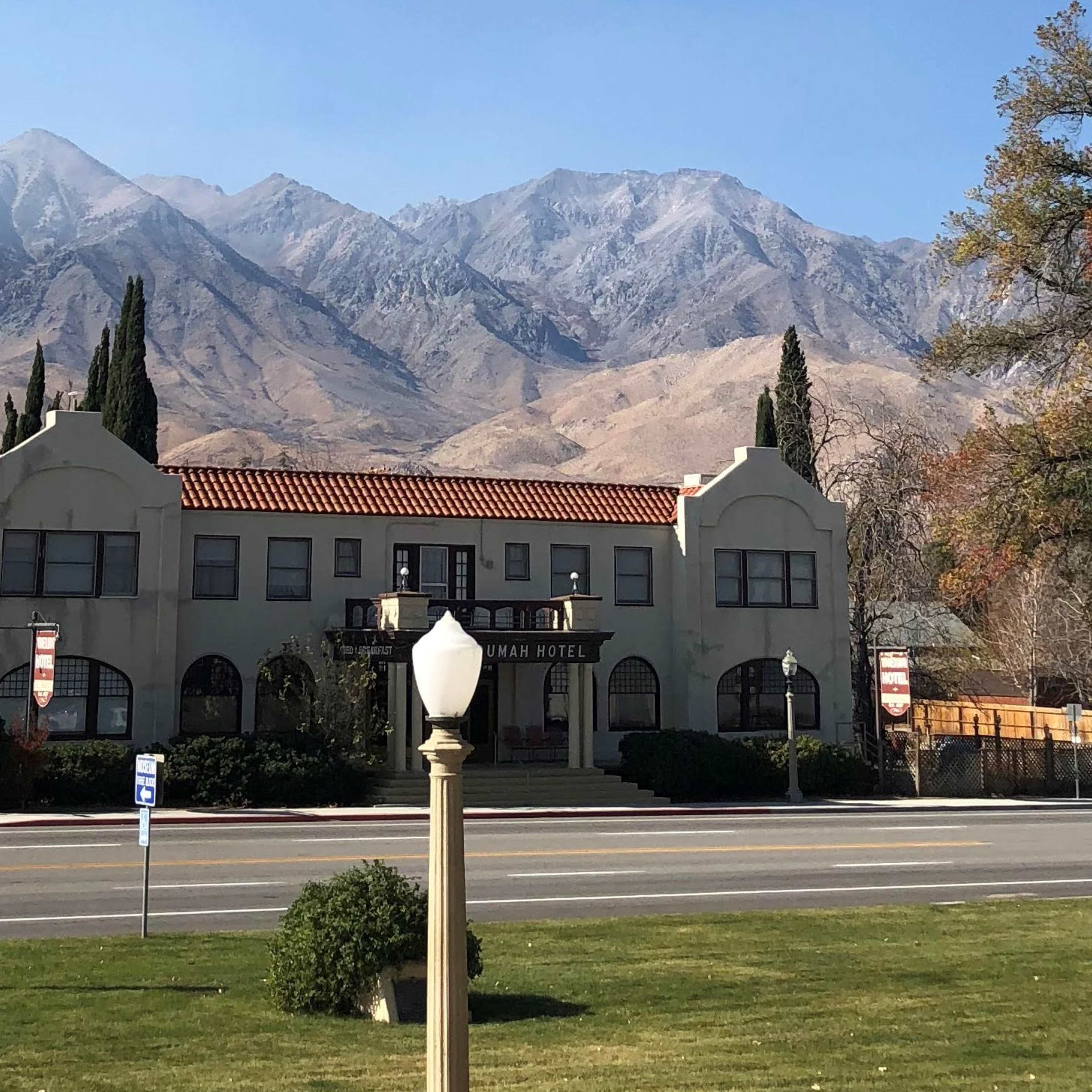 The front facade of the Manzanita Hotel, with mountains rising in the background under a clear sky.