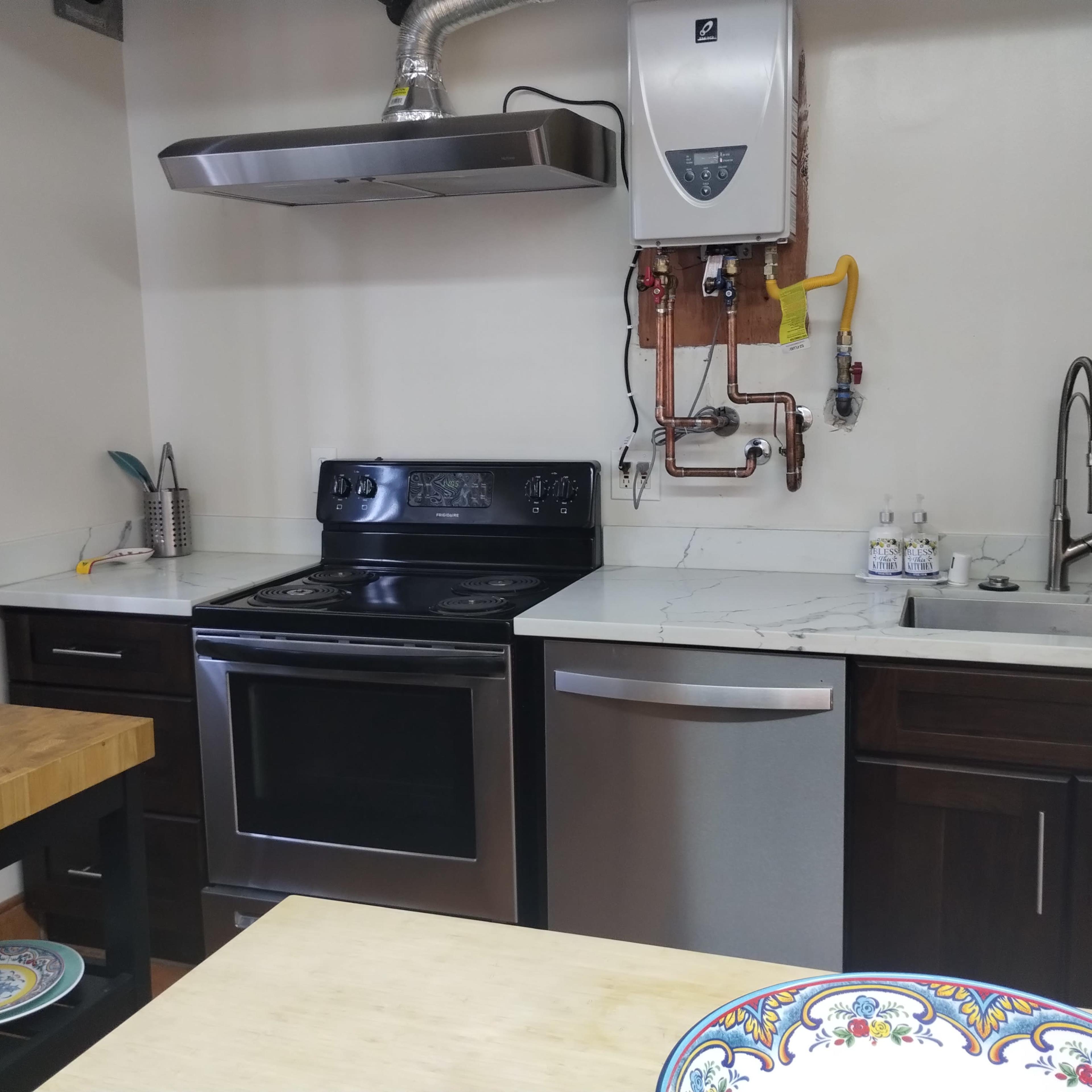 A modern kitchen with a black stove, stainless steel refrigerator, and white marble countertops.