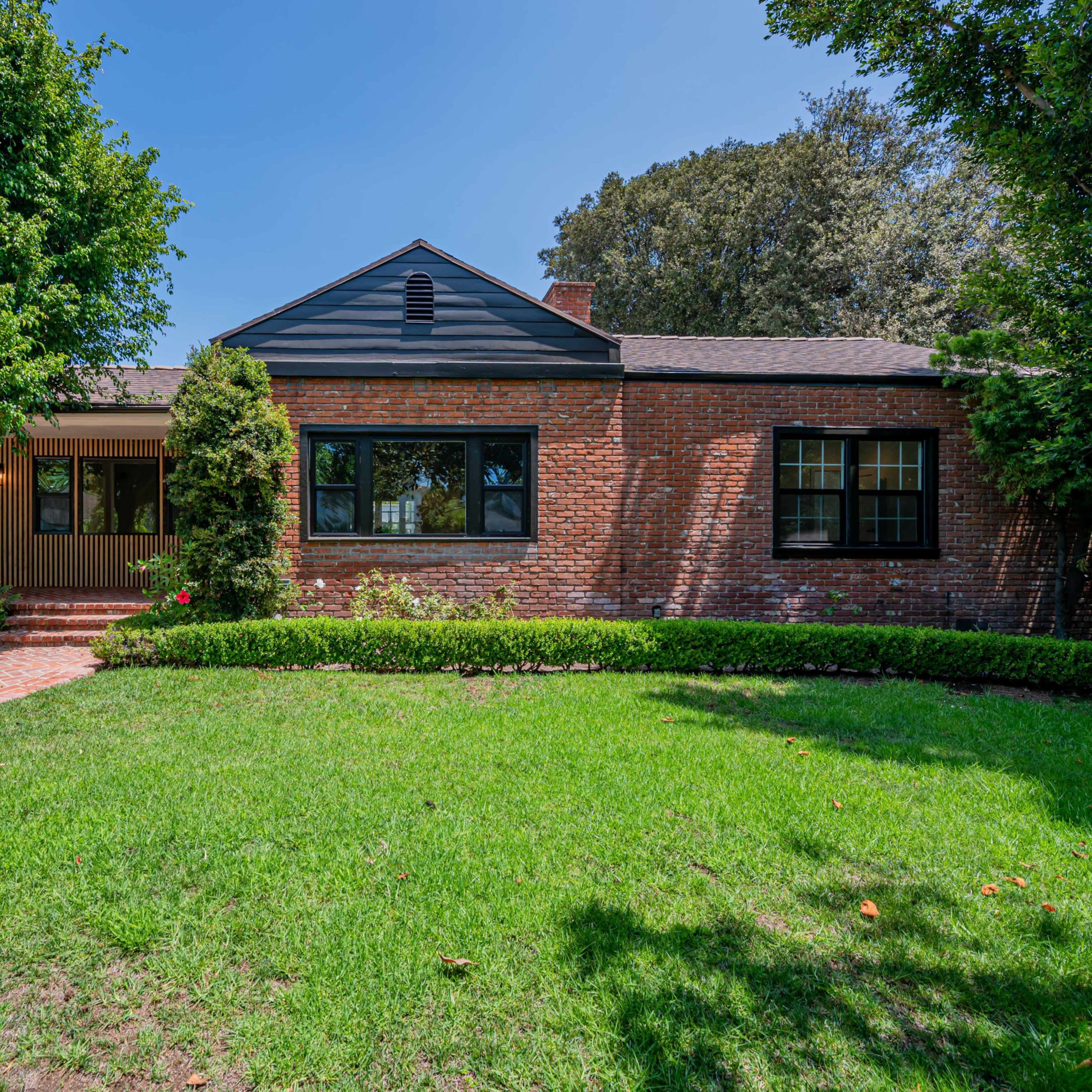 A single-story brick house with a landscaped front yard and a brick walkway leading to the entrance.
