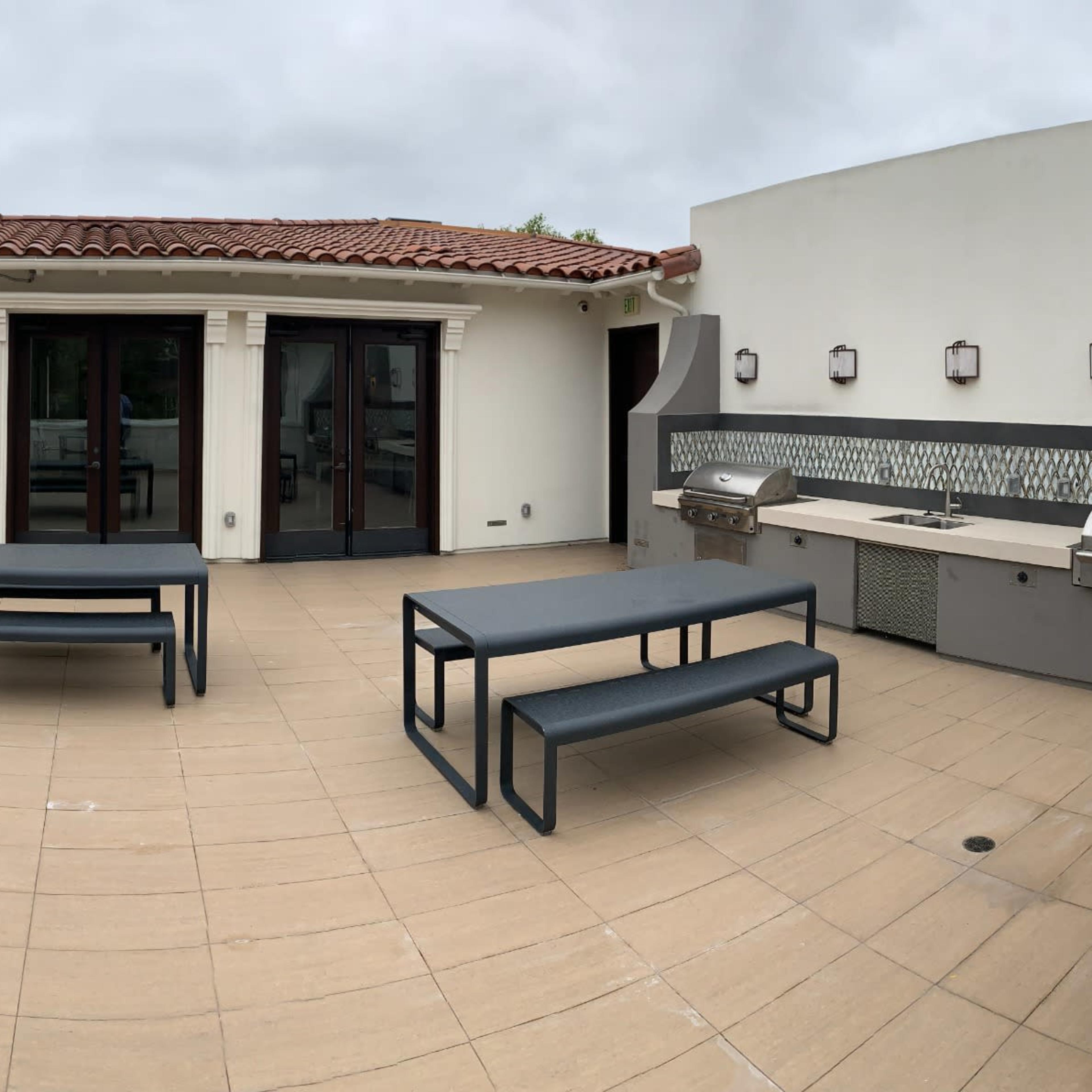 A rooftop patio featuring outdoor furniture, a barbecue area, and a fireplace.