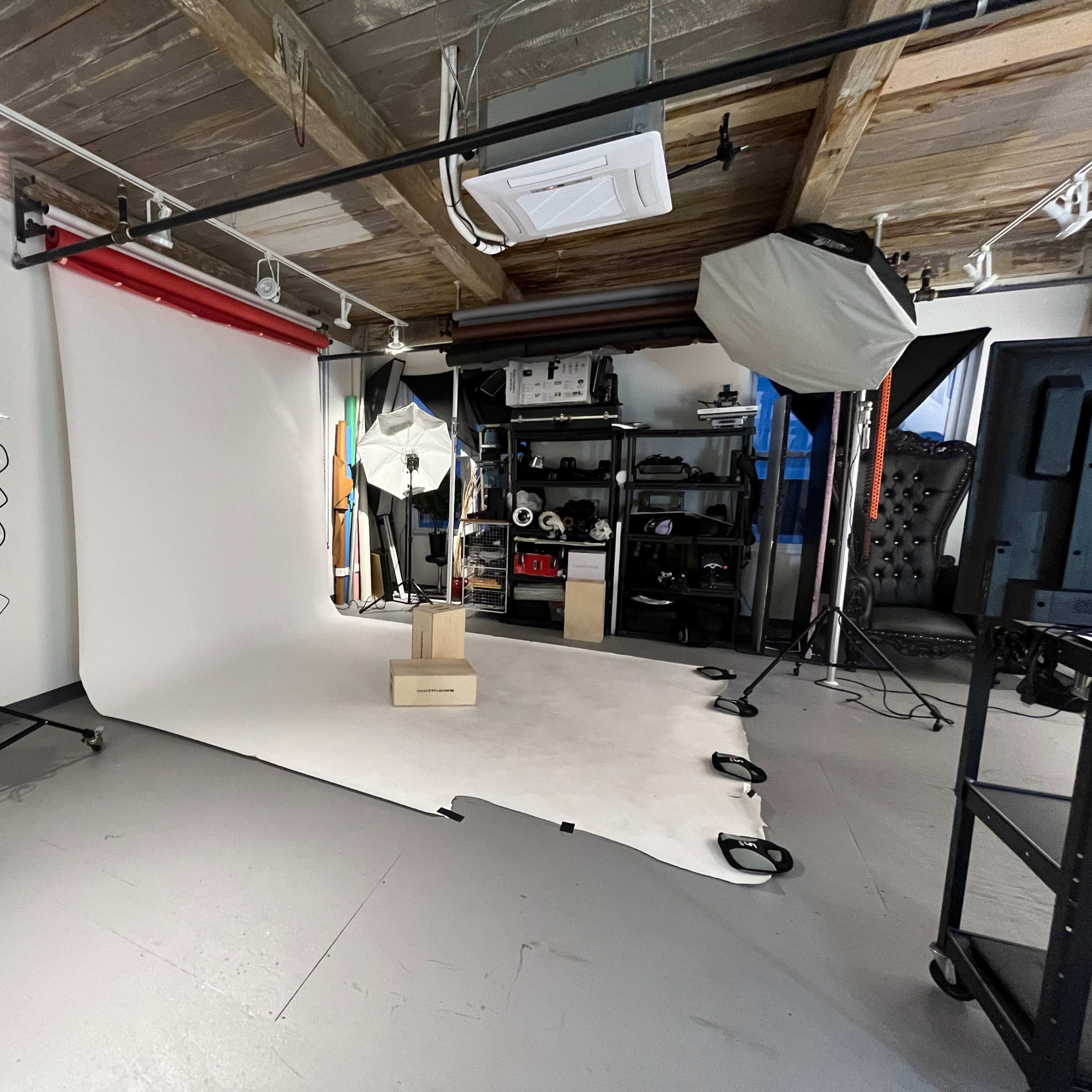 A photography studio with a backdrop, lighting equipment, and a shelf of gear.